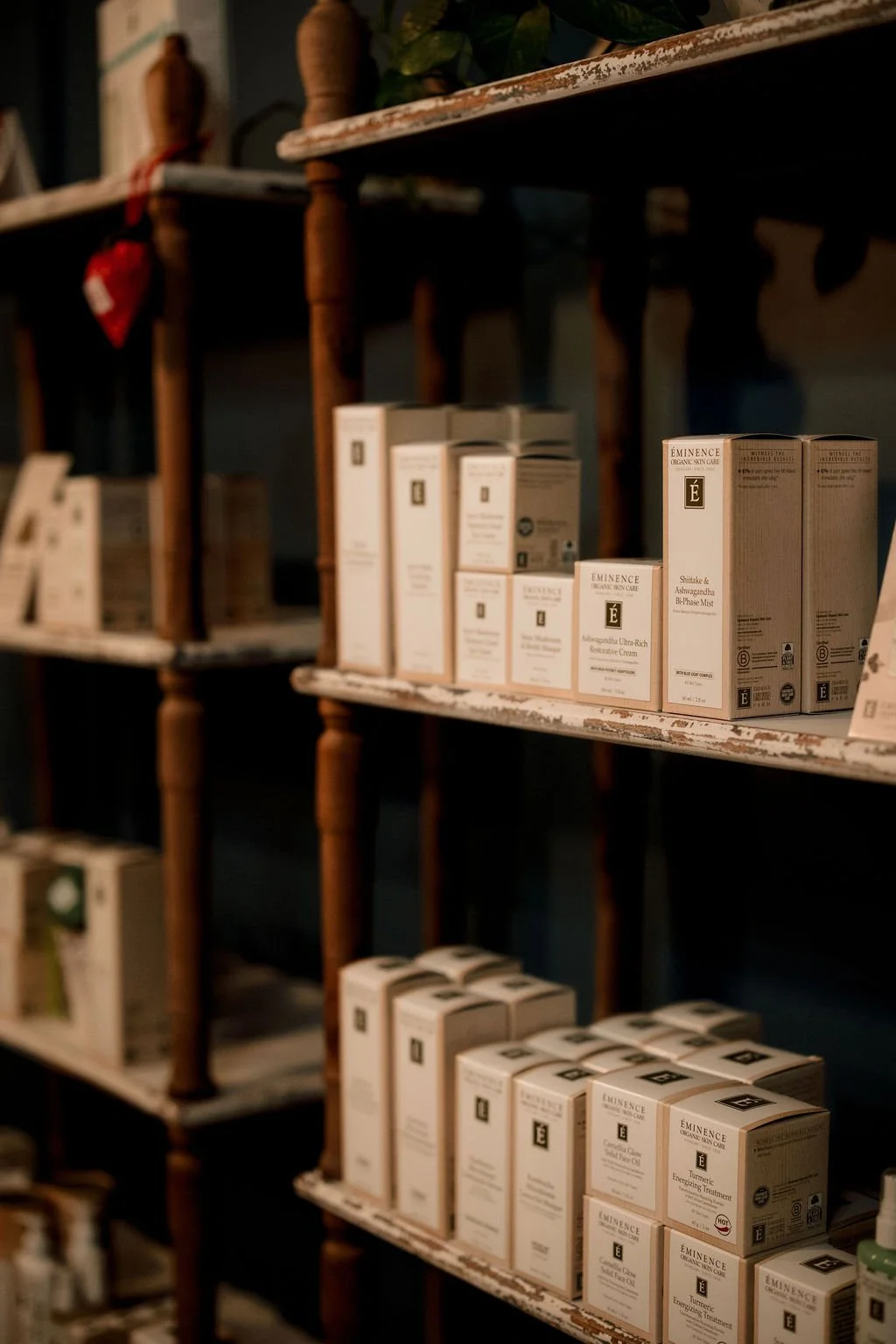 Shelves filled with skincare products and creams, including Eminence Organic Skin Care boxes, in a dimly lit retail or spa store.