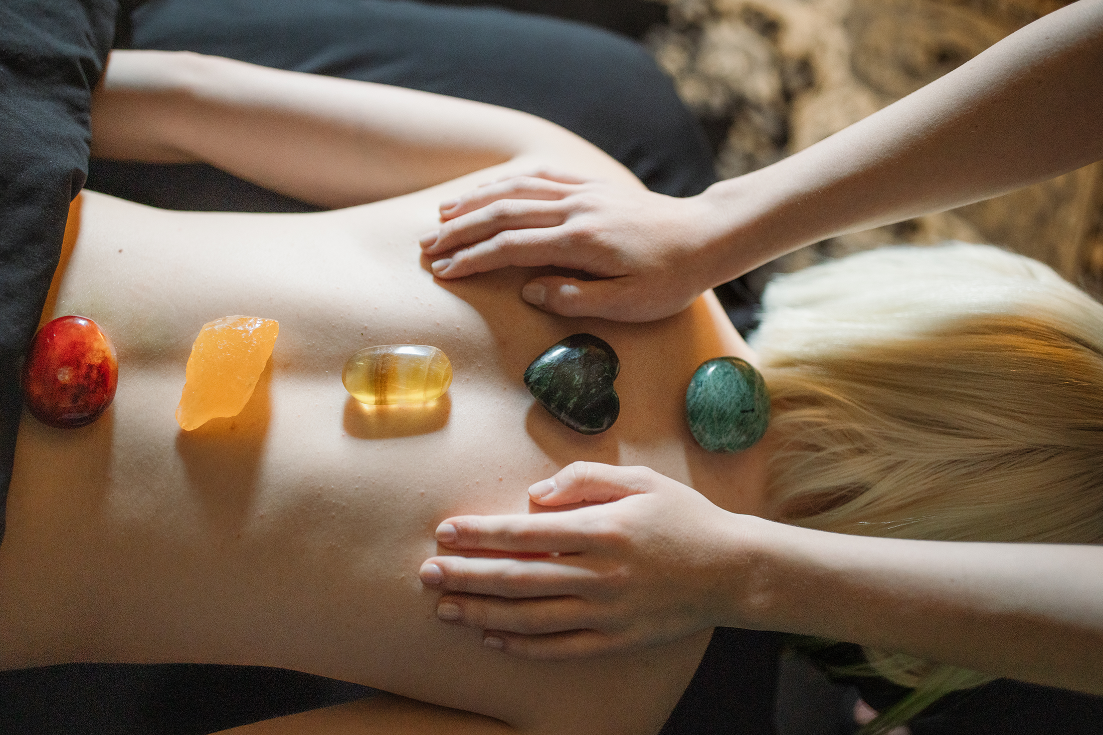 A person receiving a massage with stones placed along their back during a holistic therapy session.