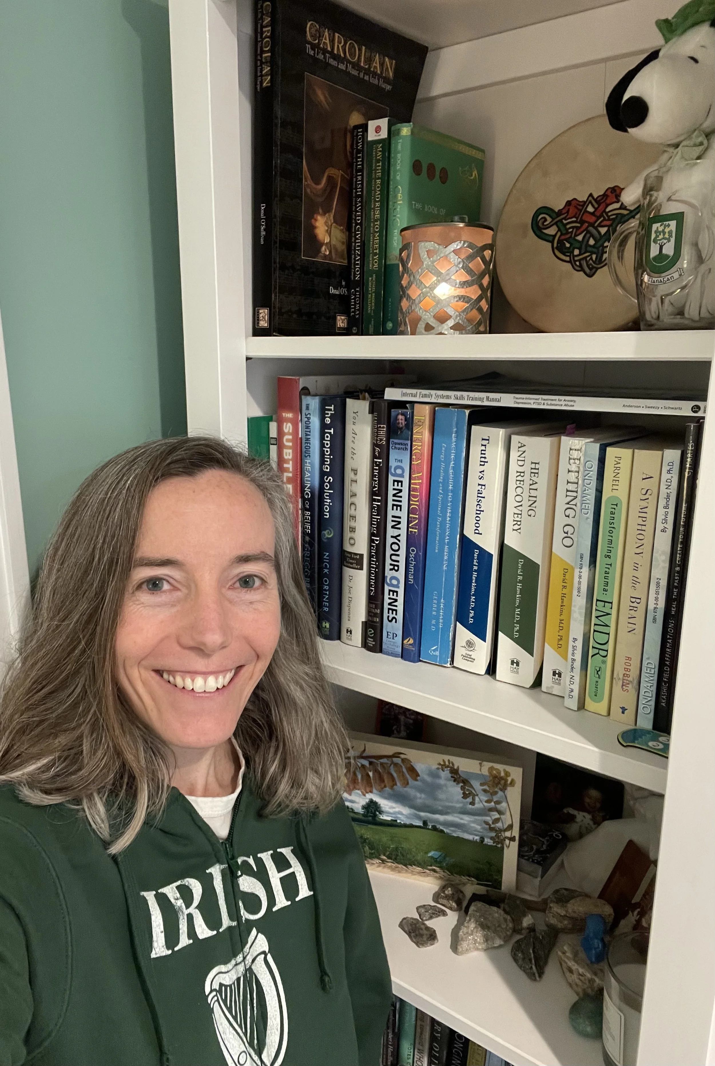 Mary VonO wearing an Irish harp sweatshirt beside books on recovery, healing, and Irish history