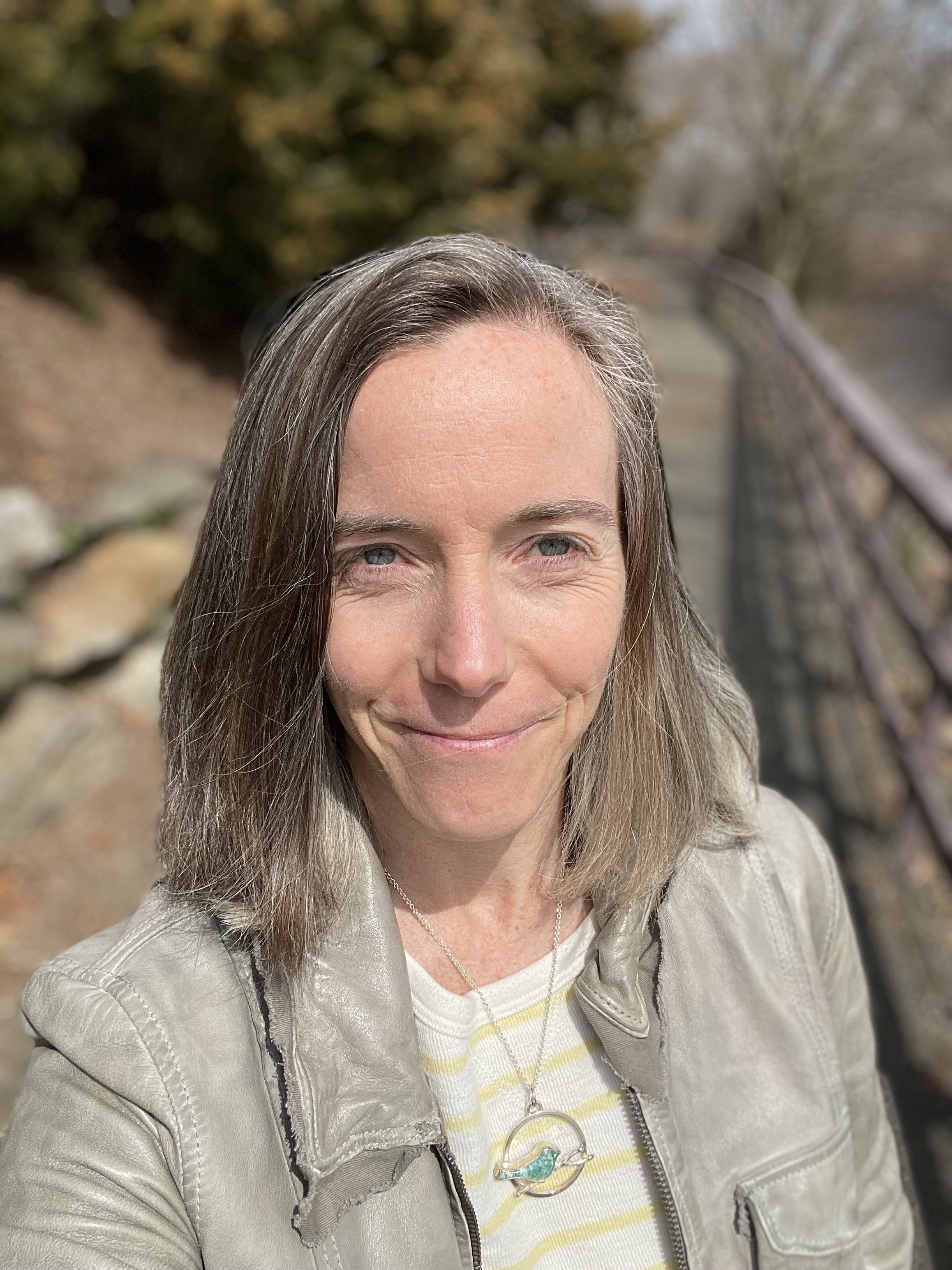 Mary VonO standing outdoors beside a winding path, looking ahead