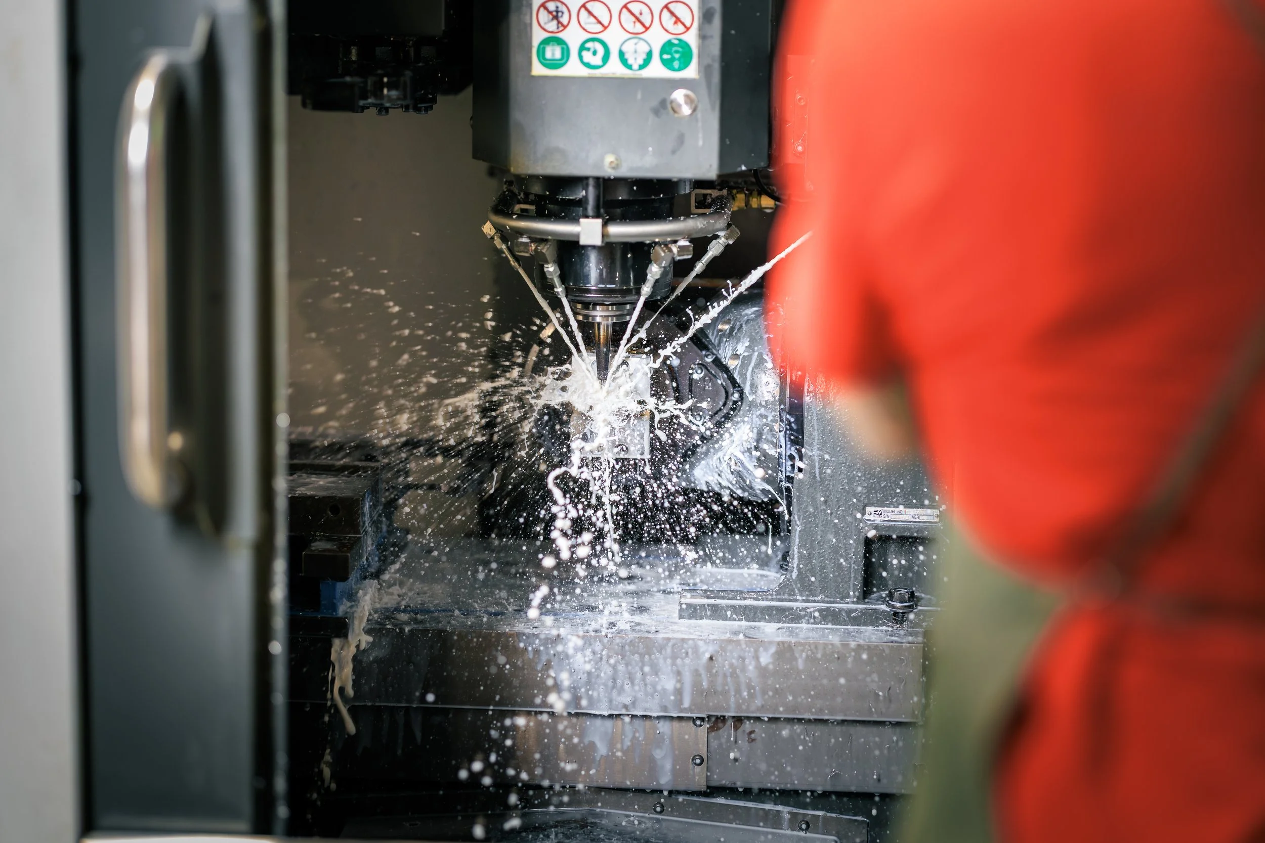 Close-up of a CNC machining process with coolant splashing as a tool cuts into metal.