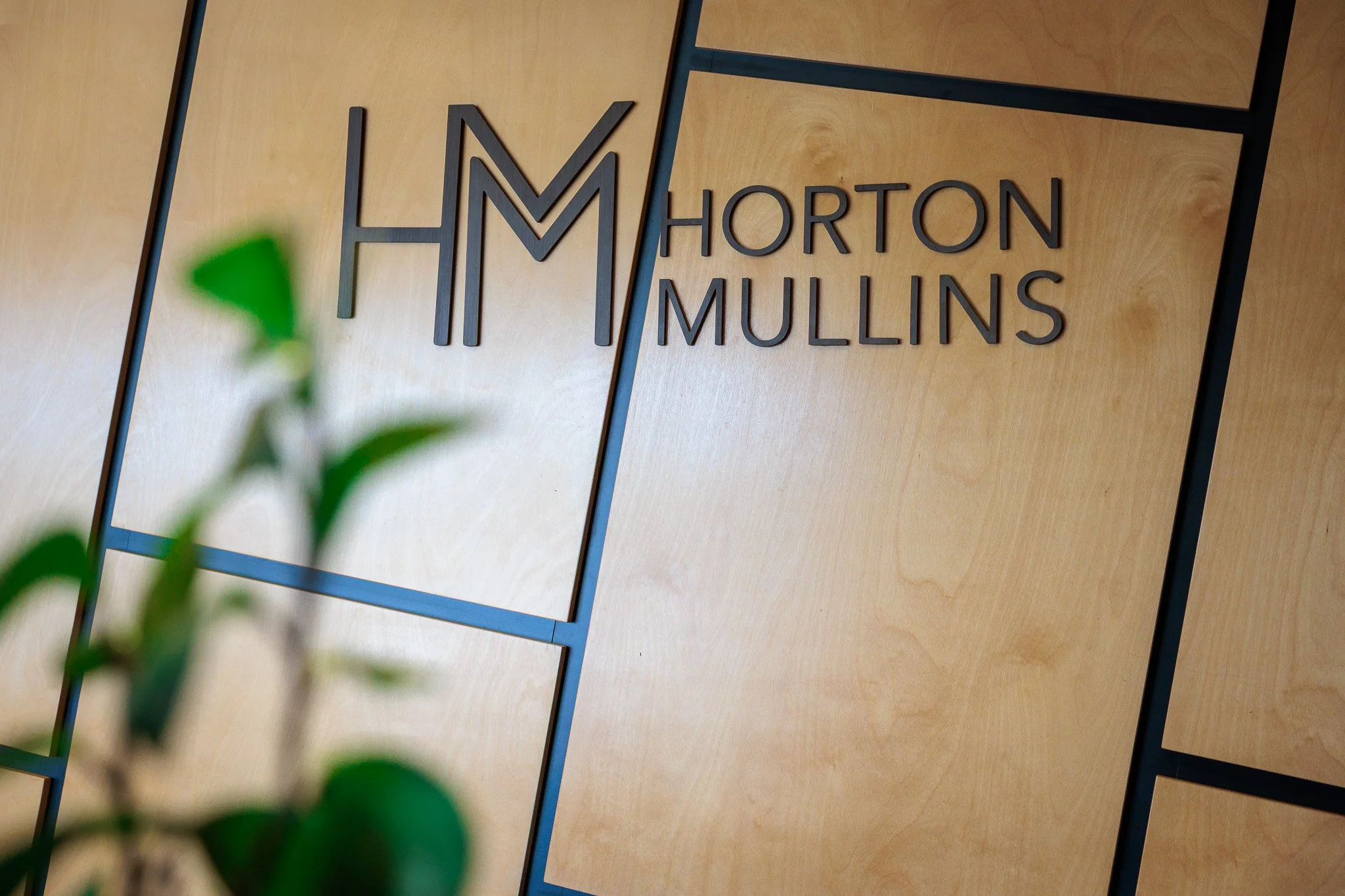 Sign on wooden wall with black metal framework reading 'H M HORTON MULLINS'