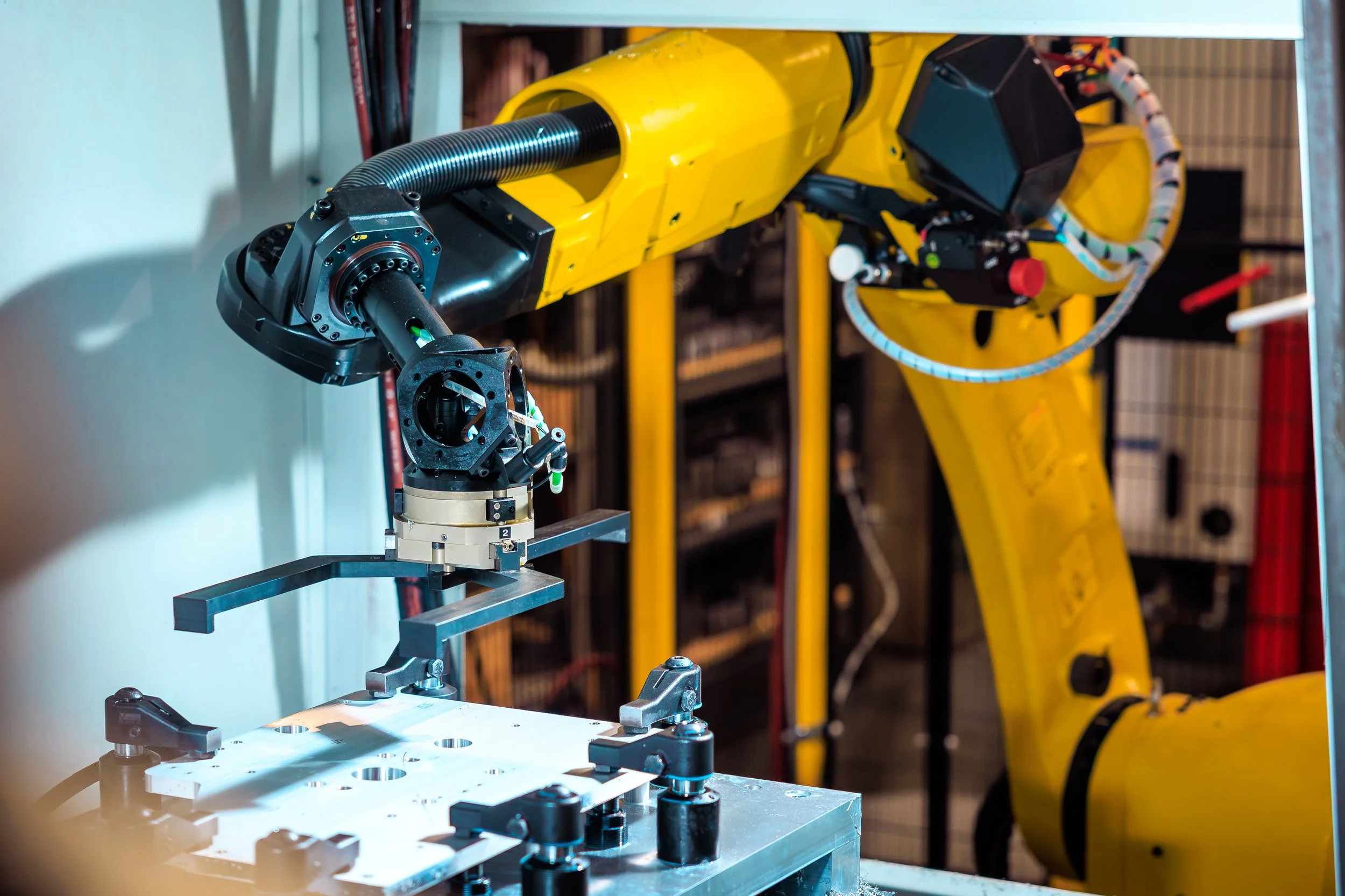 Industrial robotic arm working on a metal fixture in a workshop.