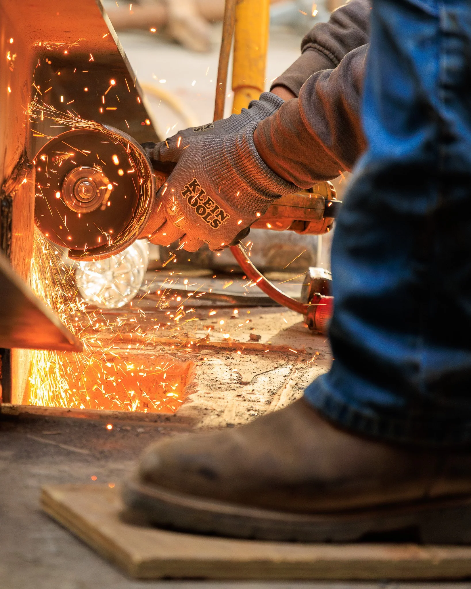 A person cutting a metal pipe with an angle grinder, sparks flying as the tool spins against the metal.