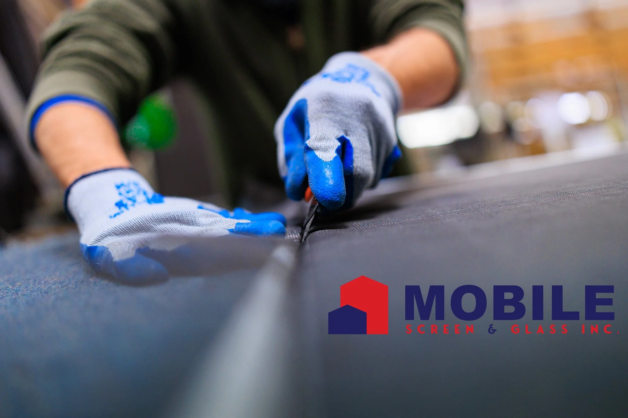 Close-up of a worker’s hands wearing blue and white gloves, installing or repairing a vinyl or rubber roofing surface inside a building with visible ceiling structure in the background.