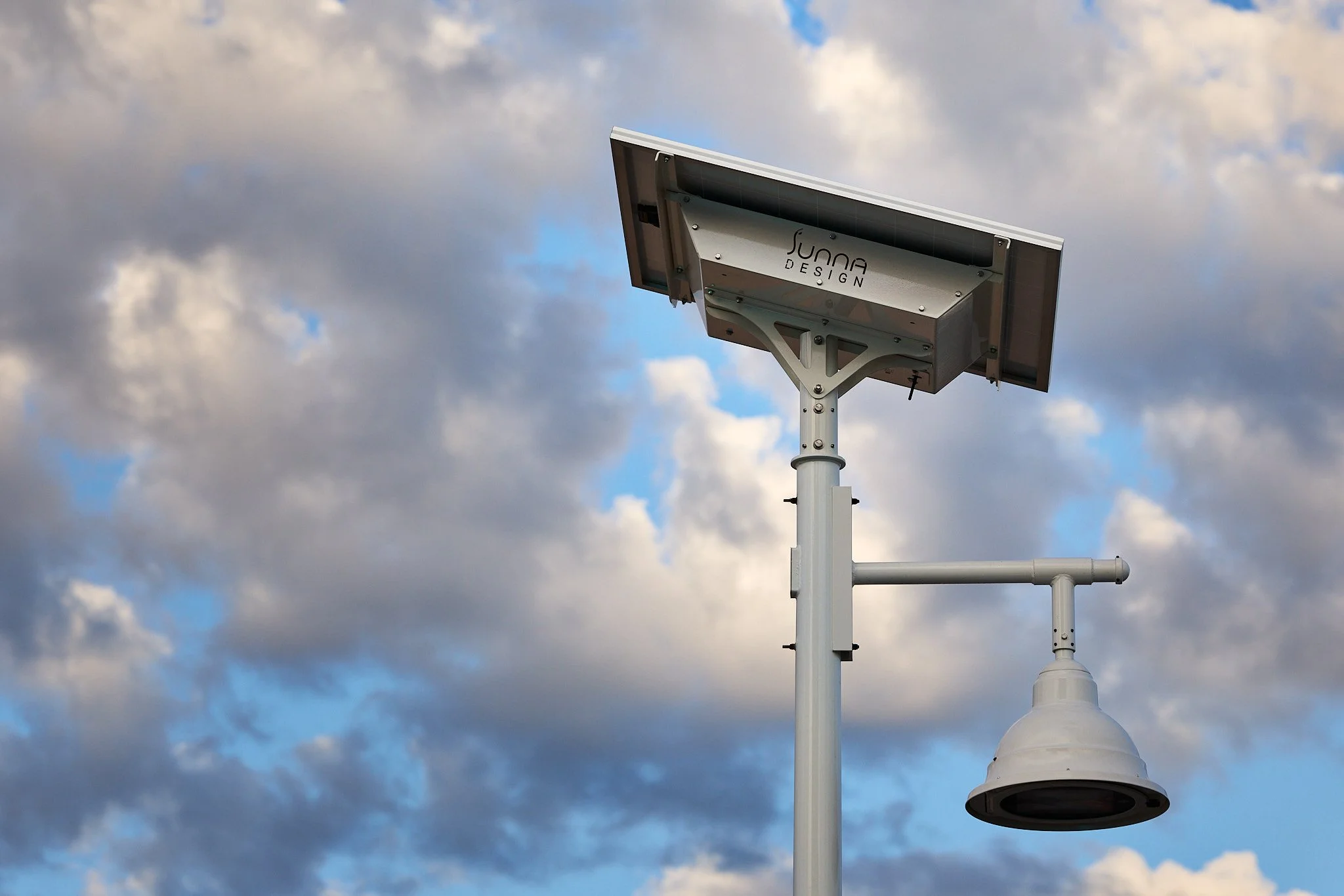 Solar-powered lighting mounted on a pole against cloudy sky.