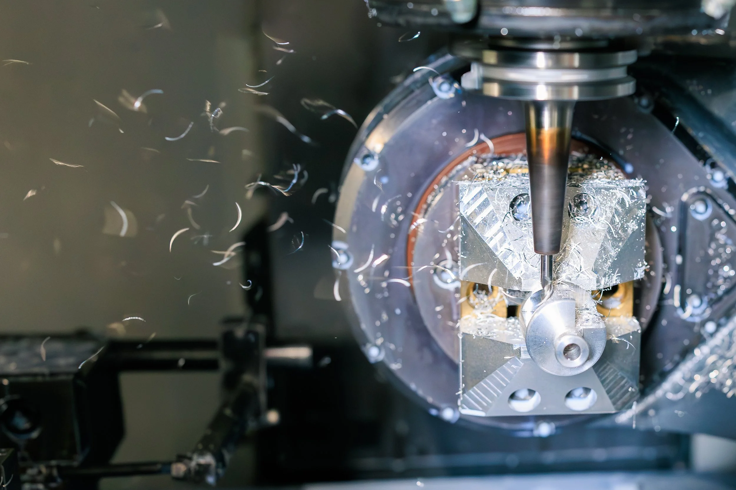 Close-up of a CNC machine cutting metal, with metal shavings around the cutting tool.