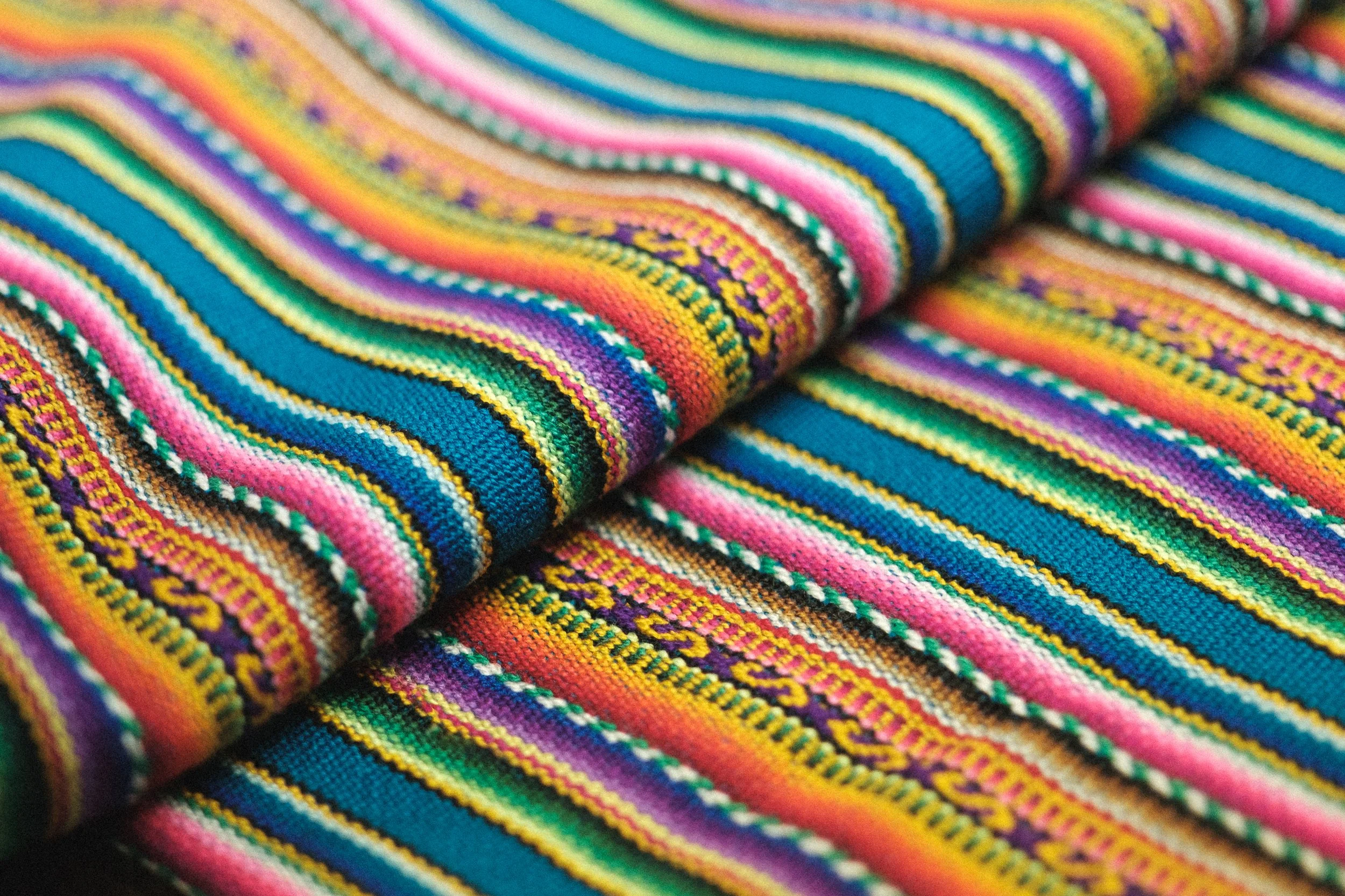 Close-up of colorful woven fabric with stripes in pink, blue, green, yellow, purple, and black.