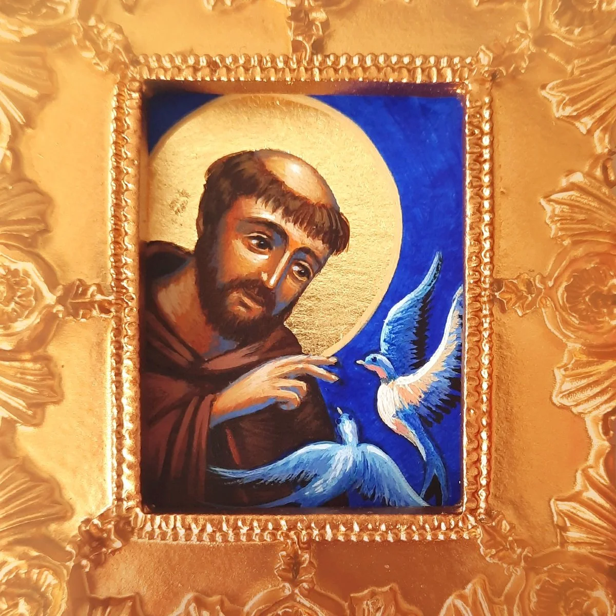 Byzantine Catholic icon of St. Francis of Assisi blessing two birds. The icon is surrounded by a golden ornate frame.