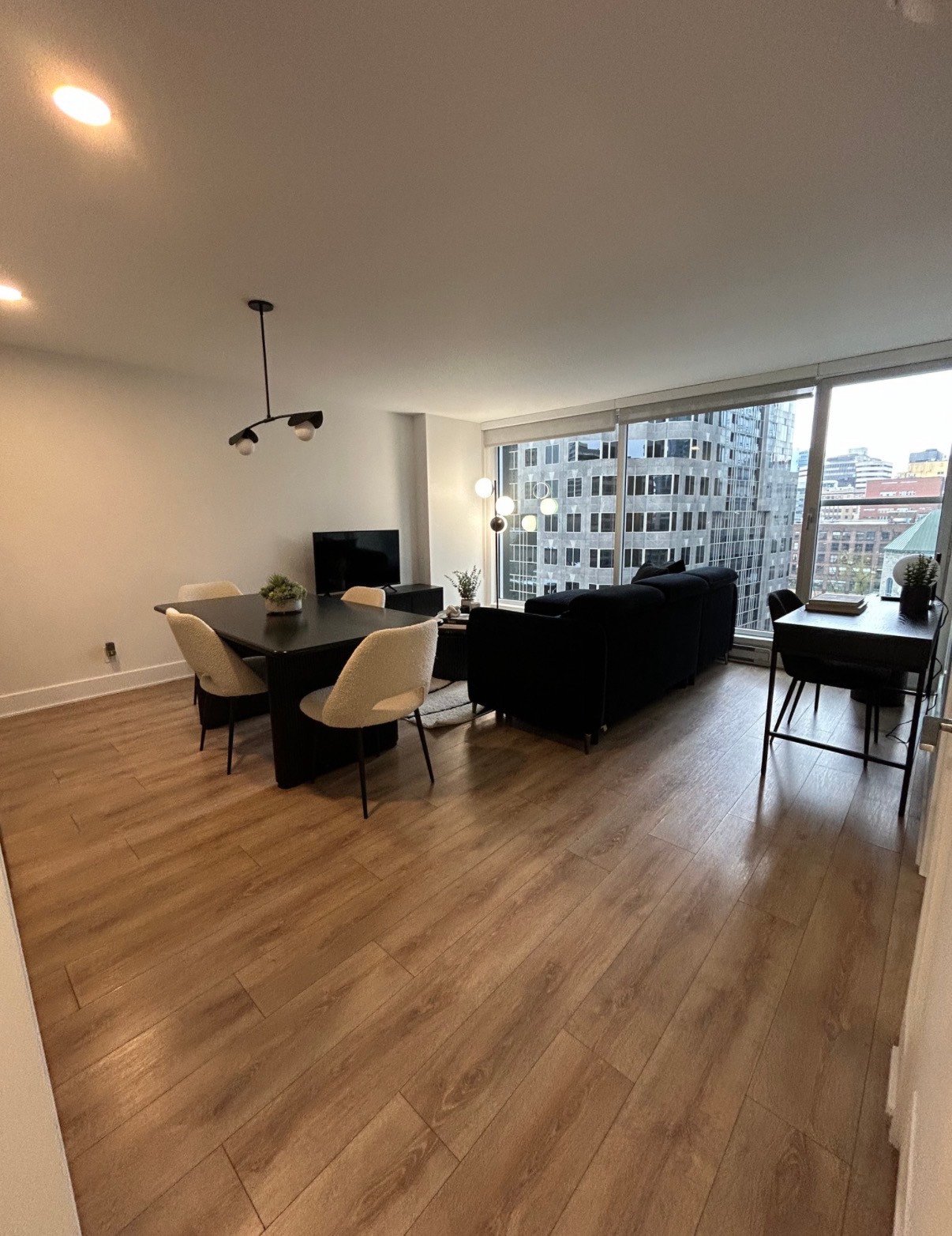 Salon et salle à manger lumineux avec canapé, table et plancher de bois
