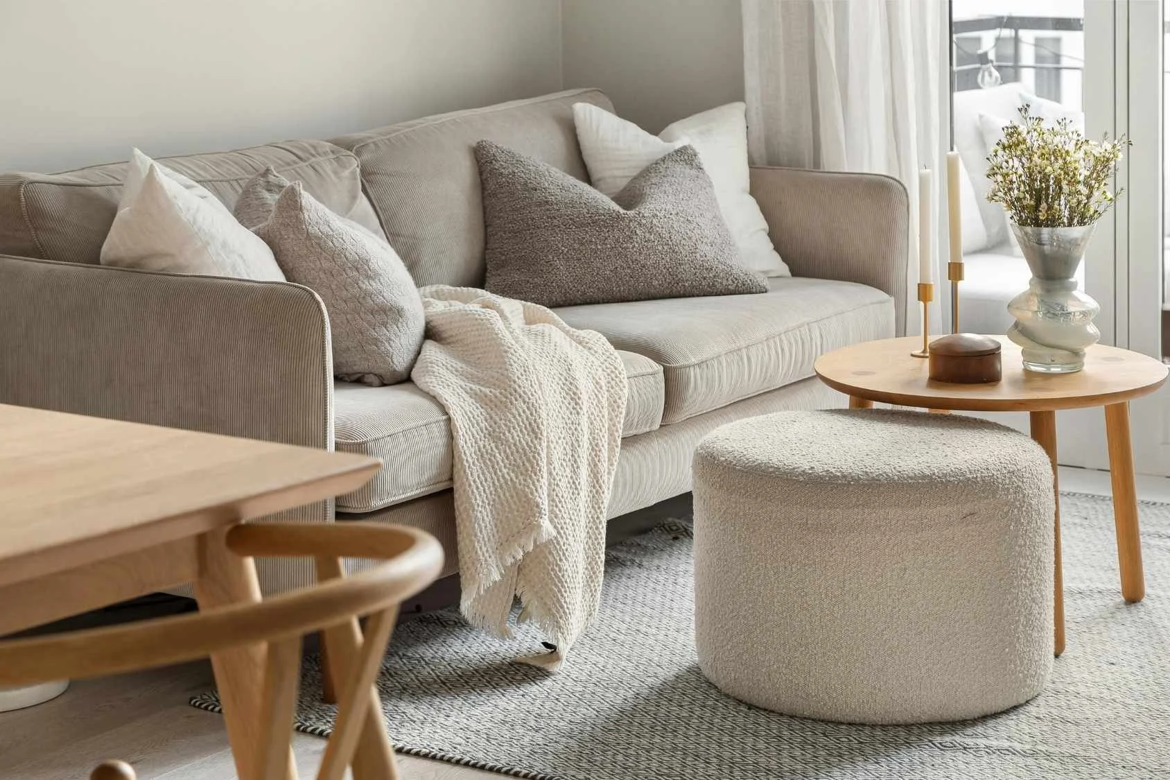 A cozy living room with a beige striped sofa decorated with white and textured pillows.