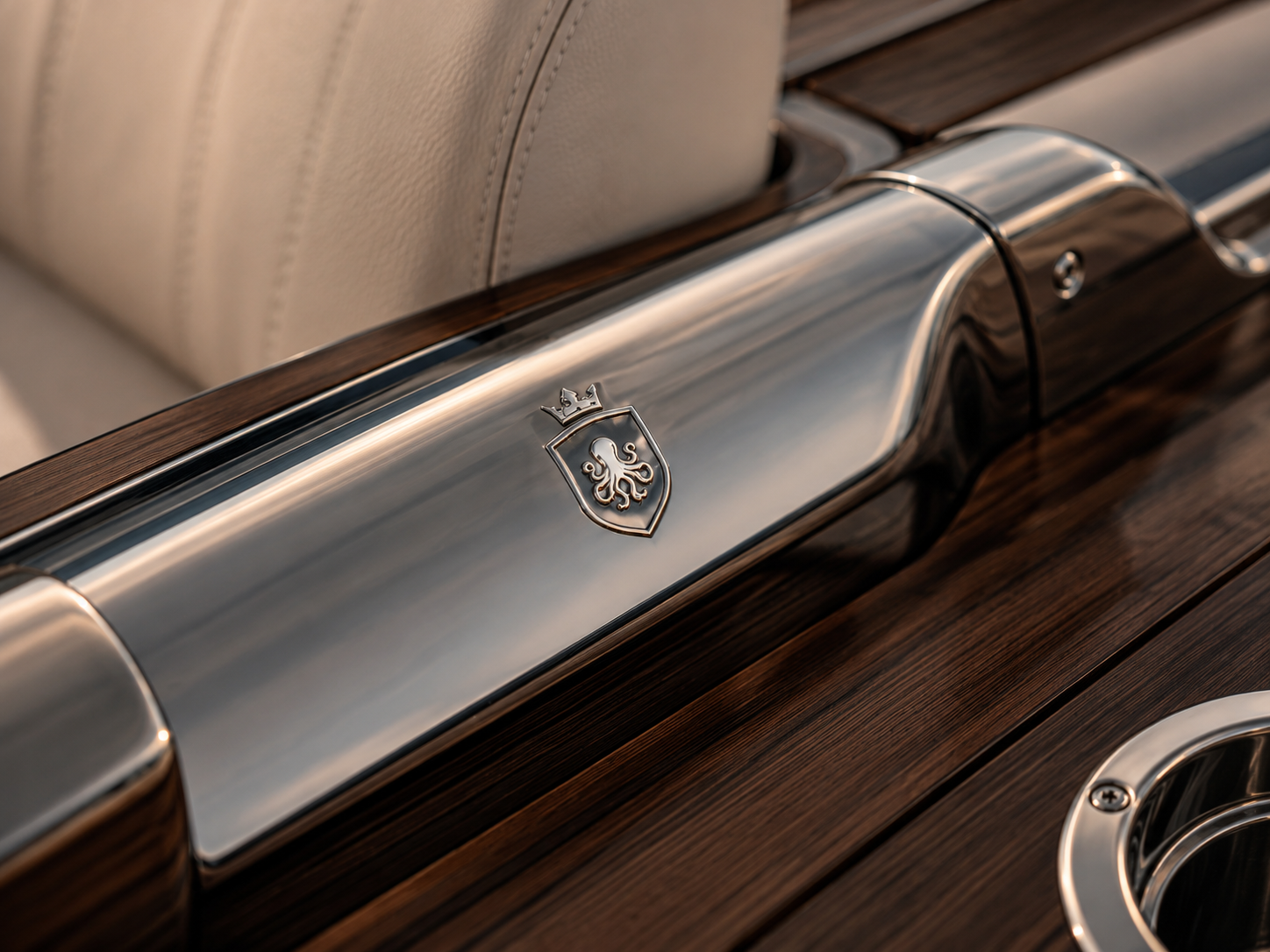 Close-up of a vintage car with a chrome trim and a crest emblem, showing beige leather interior and wooden paneling.