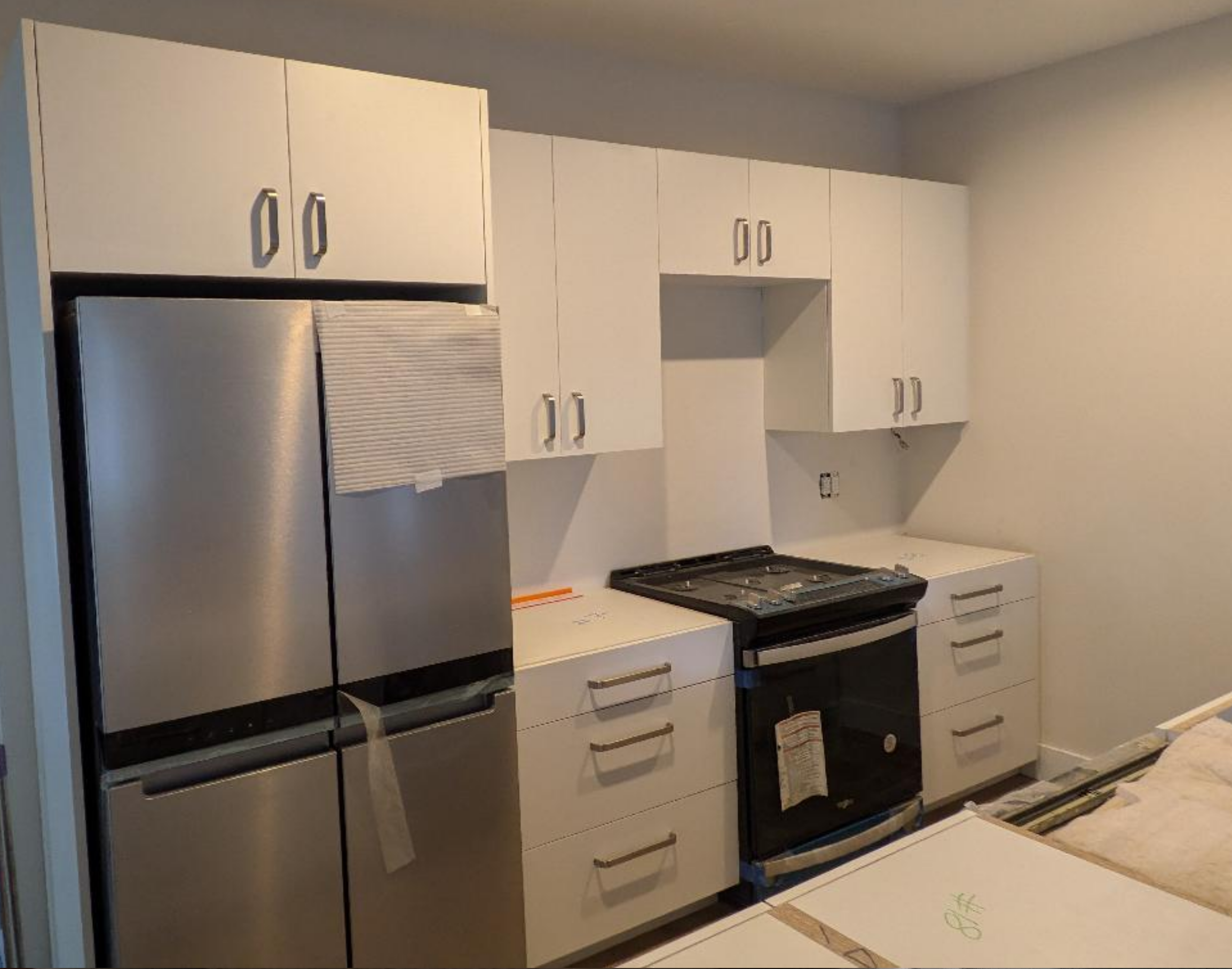 New custom made white kitchen cabinets and a stainless steel refrigerator in a home renovation project.