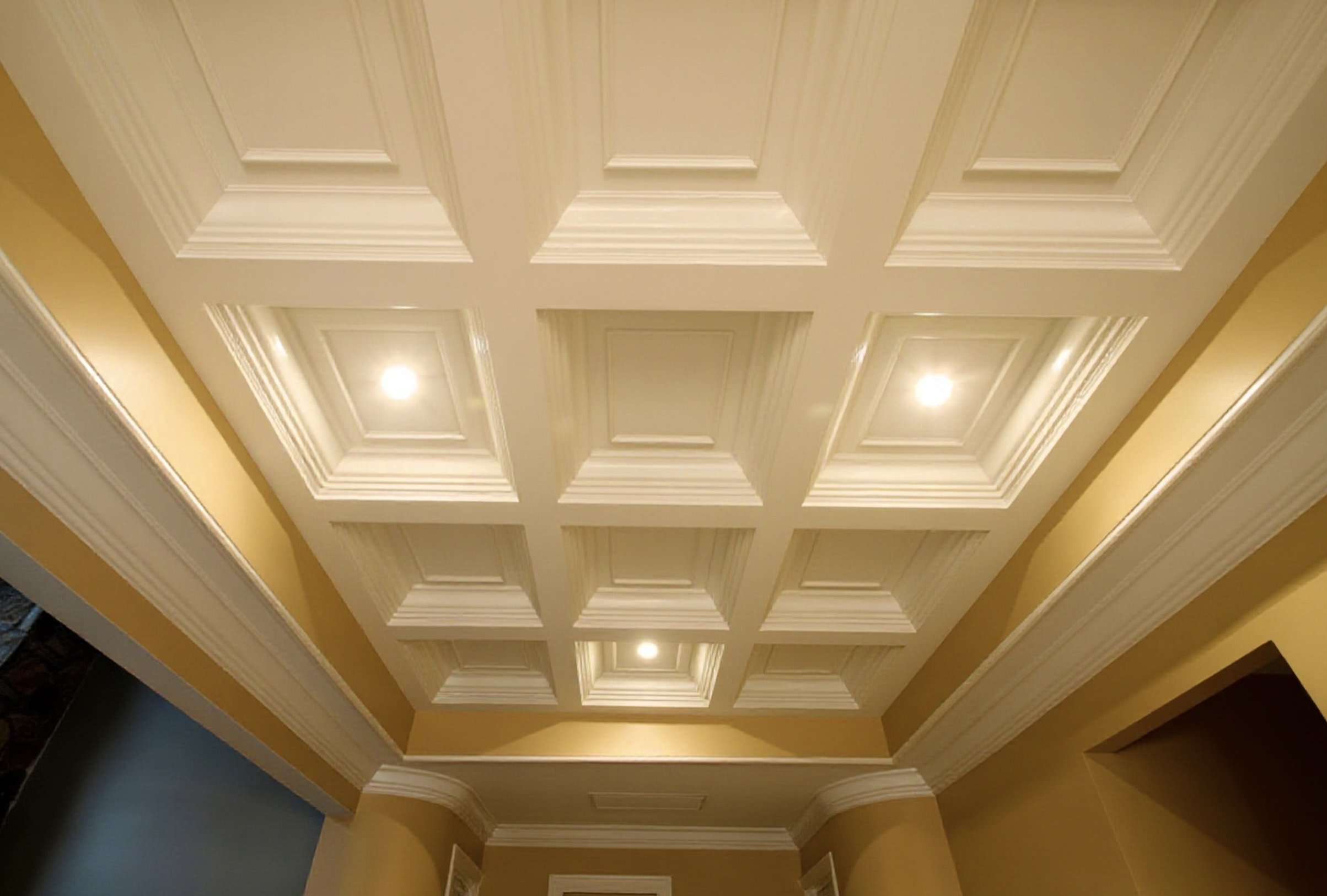 Custom-ordered coffered ceiling with decorative panel molding, recessed lighting, and yellow walls.