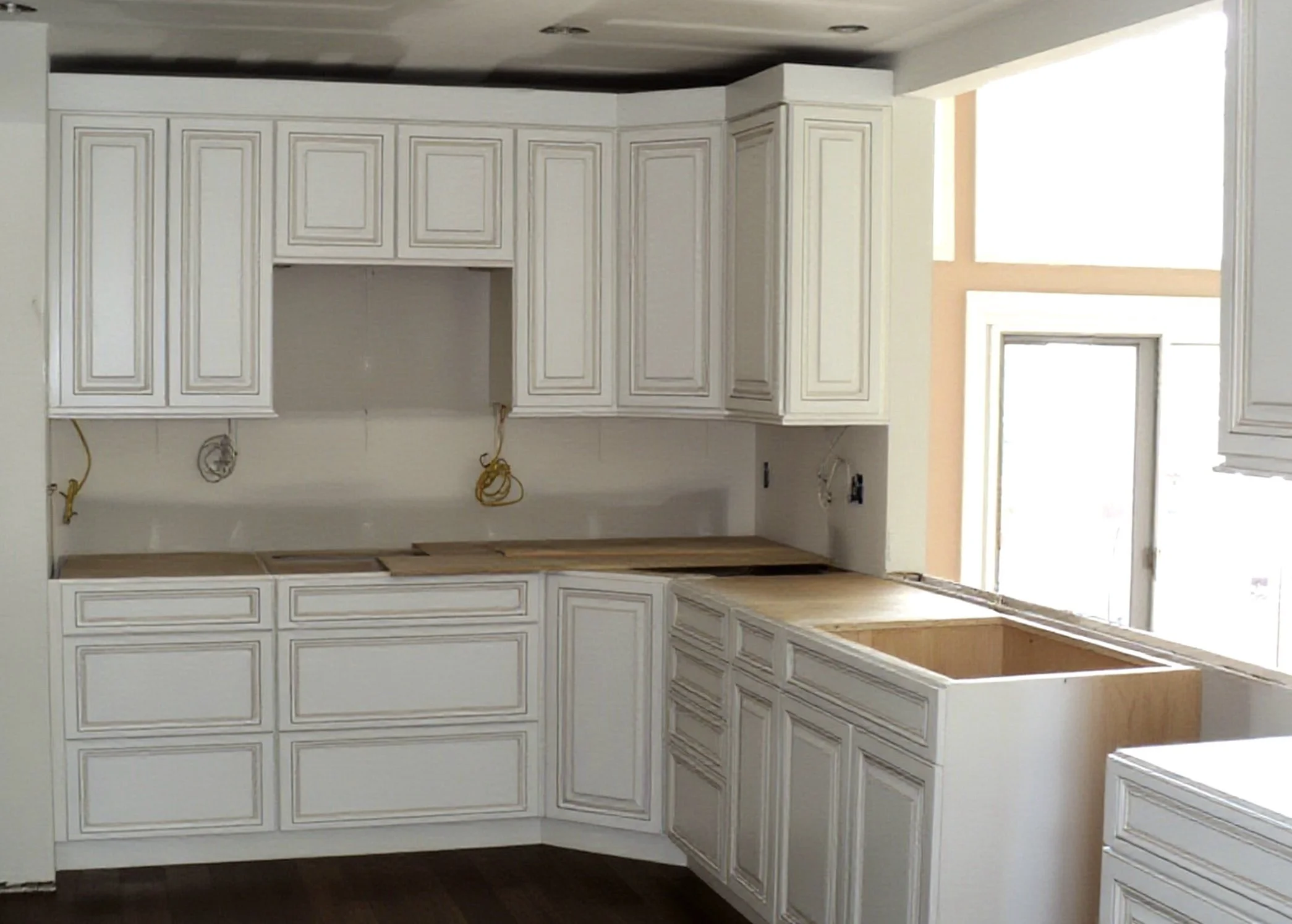 White kitchen with full custom cabinetry next to a window letting in natural light.