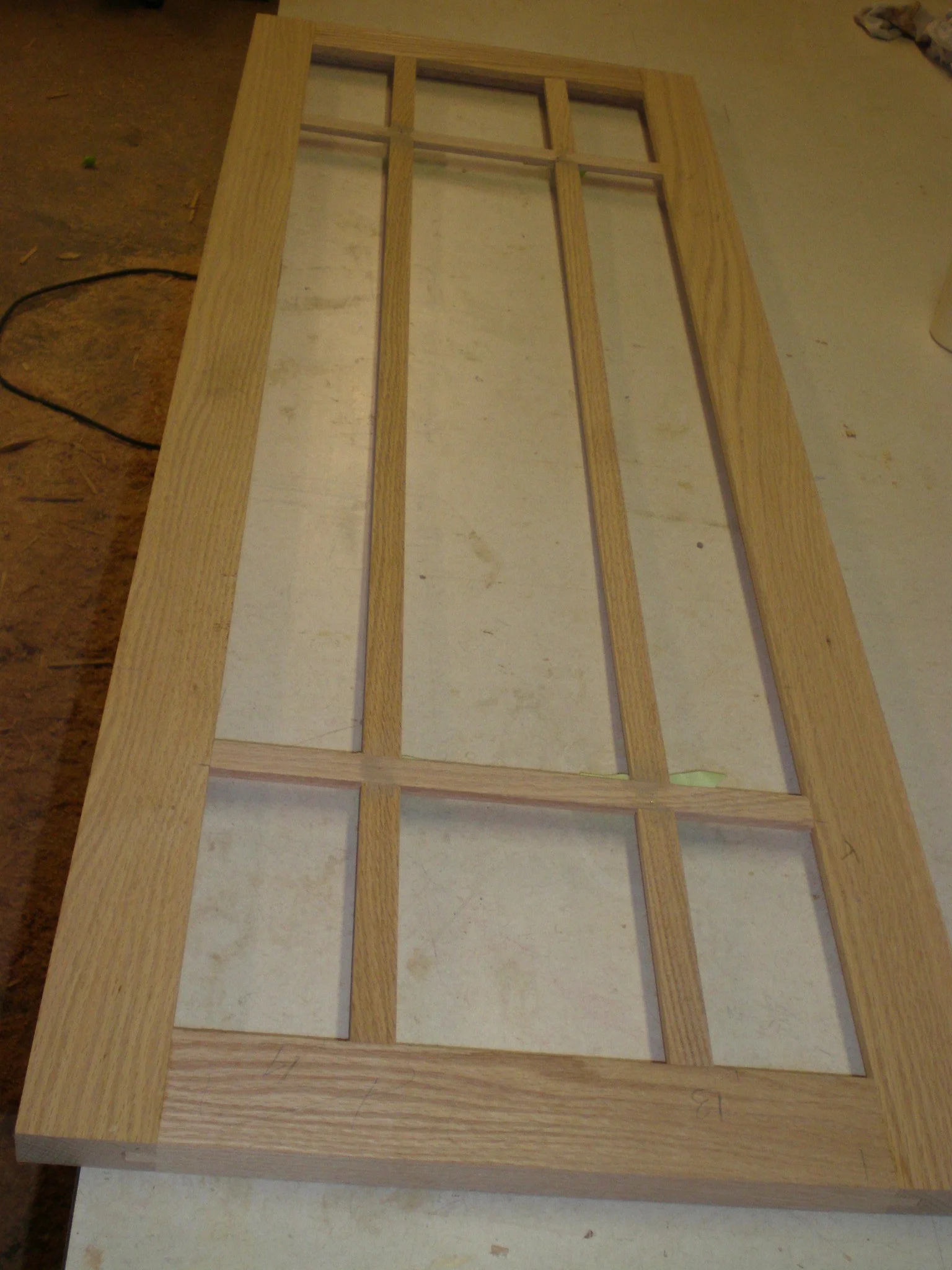 A custom wooden frame with rectangular and square compartments resting on a light-colored table or work surface.