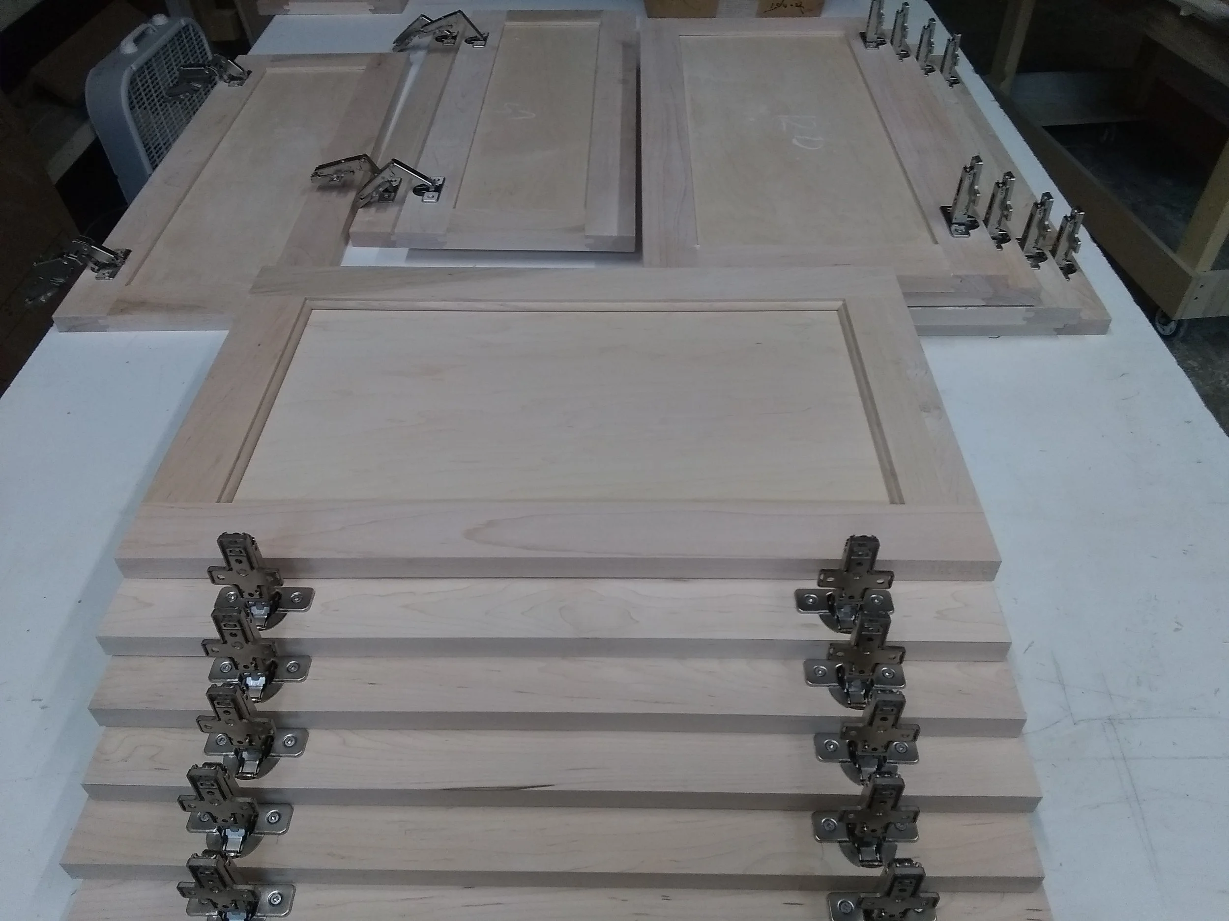 Locally made wooden cabinet doors stacked on a worktable in a woodworking shop.
Custom cabinetry. Kitchen cabinets made of solid  wood and satin , water base finish.
#bigjohnsco #CustomFurniture #MadeFromScratch #HomeRemodeling #KitchenRemodel #MadeF