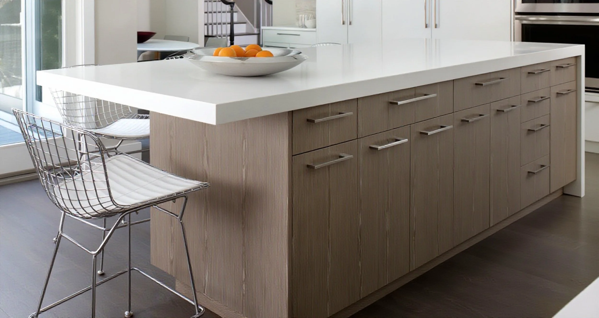 Modern kitchen island with a white countertop and custom light-colored wood cabinets.