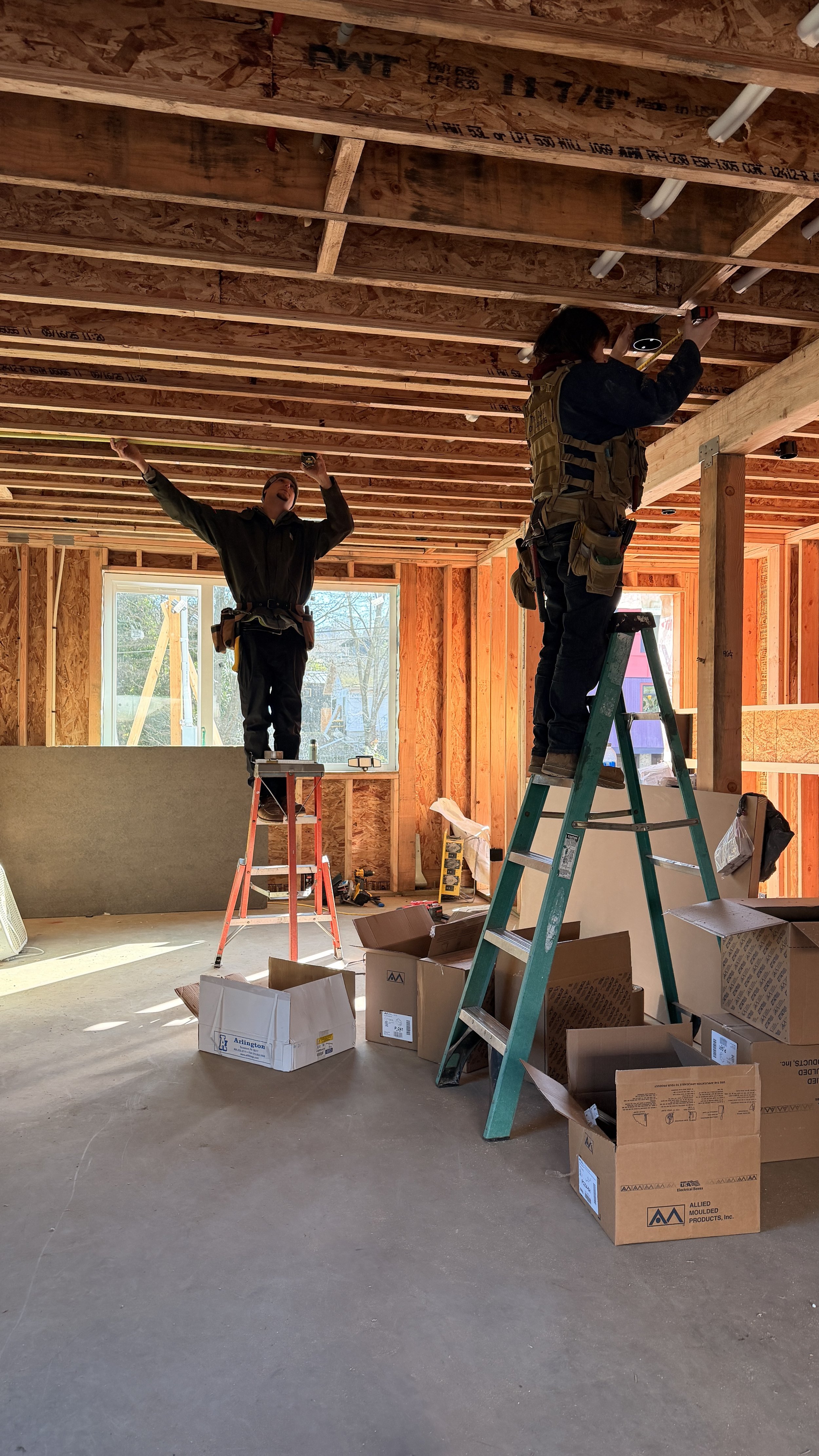 Electrician laying out recessed can light locations during new home construction.