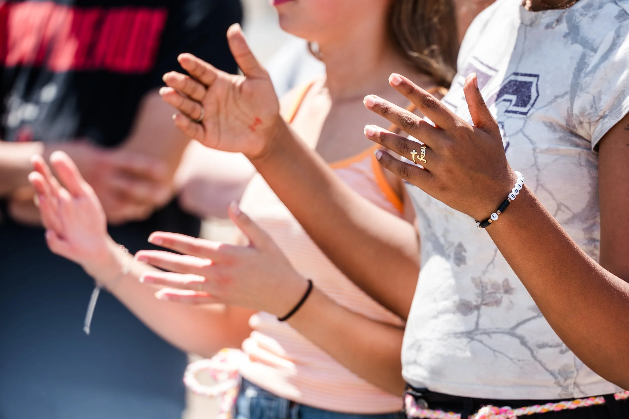 People kneeling with hands raised in prayer or meditation outdoors.