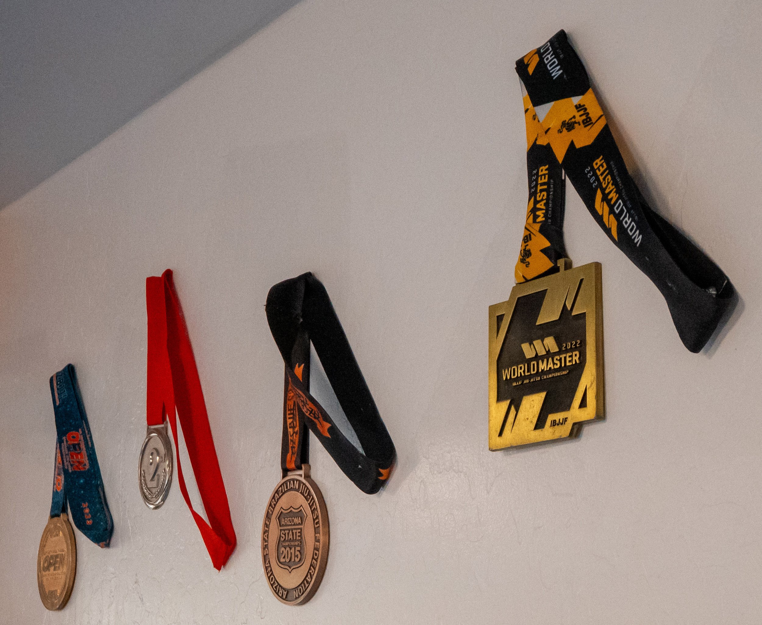 Wall display of medals and awards related to martial arts competitions, including medals from the IBJJF World Master Championship.
