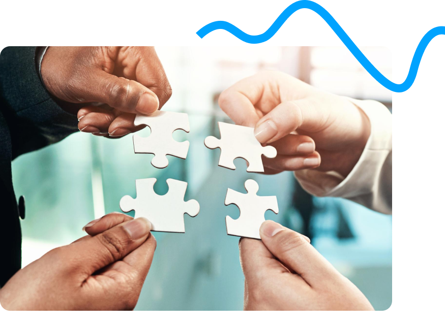 Four hands holding four separate white puzzle pieces, fitting them together in a collaborative effort.
