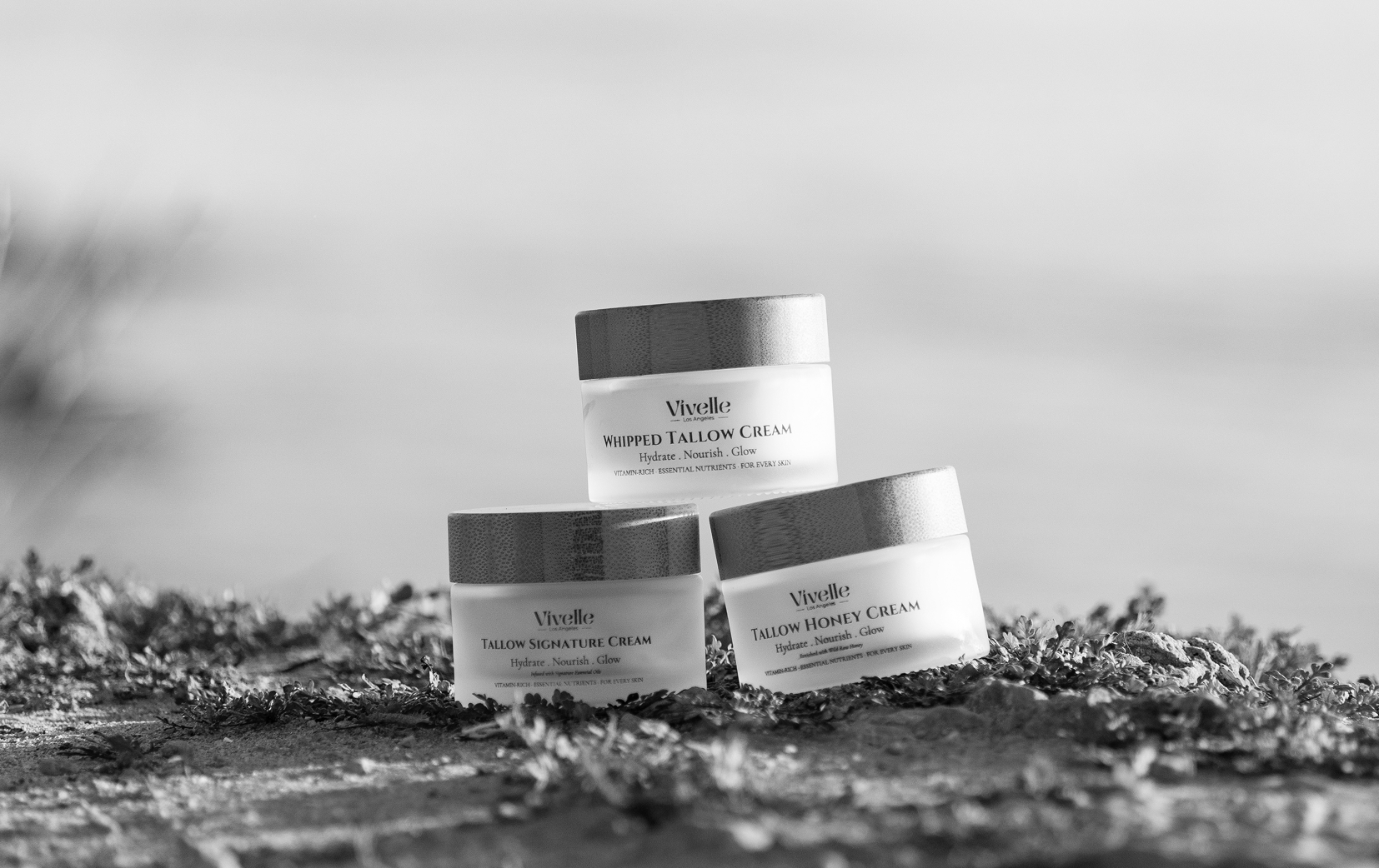 Three jars of Vivelle skincare cream on a natural outdoor surface with blurred background.