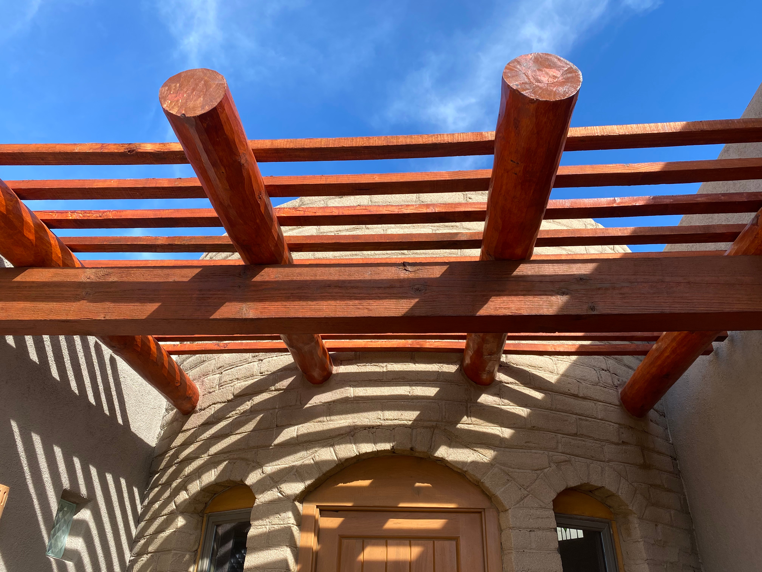 Redwood beams installed on a stone archway under a clear blue sky