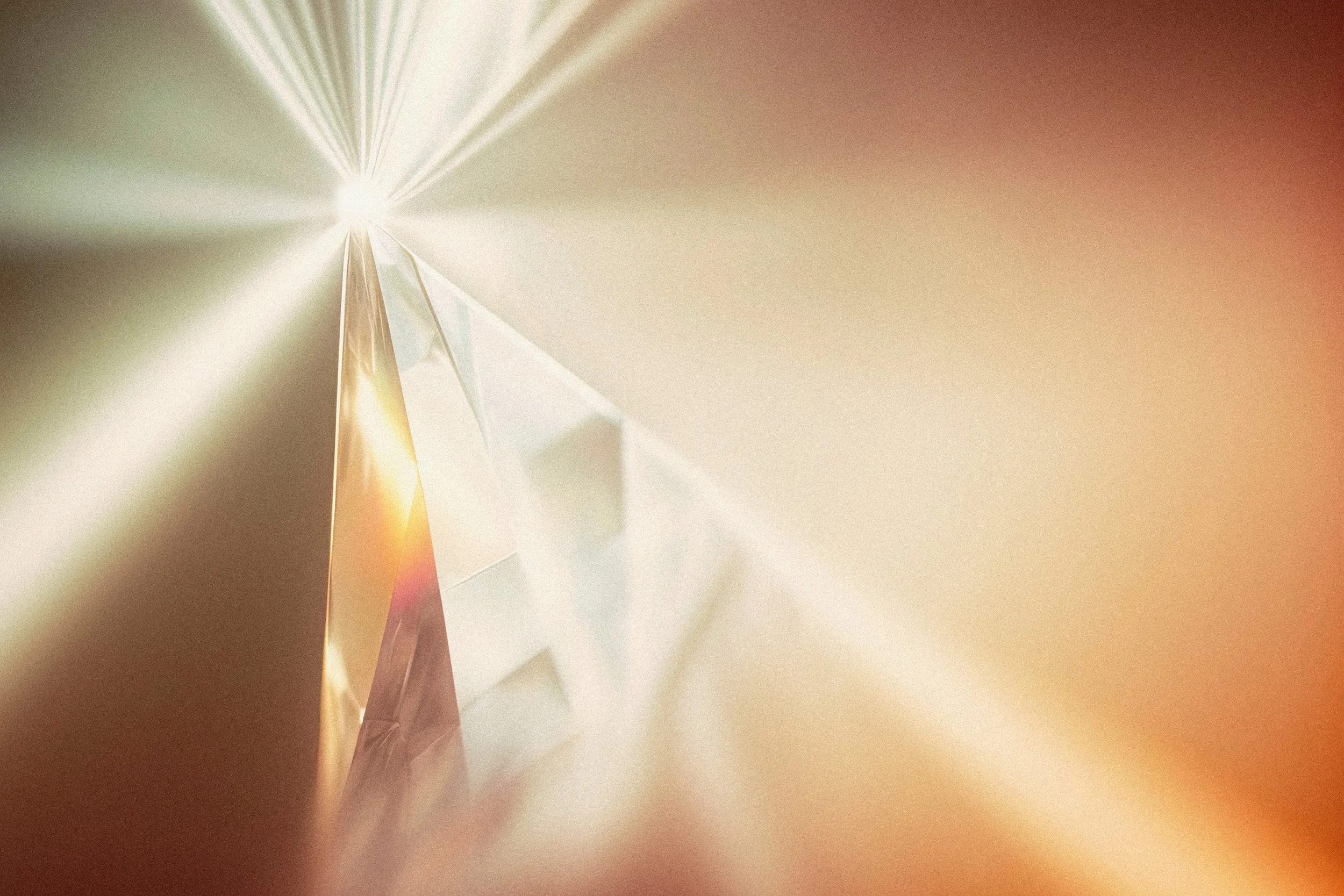 Close-up of a transparent, faceted crystal reflecting light with a gradient background of warm colors.