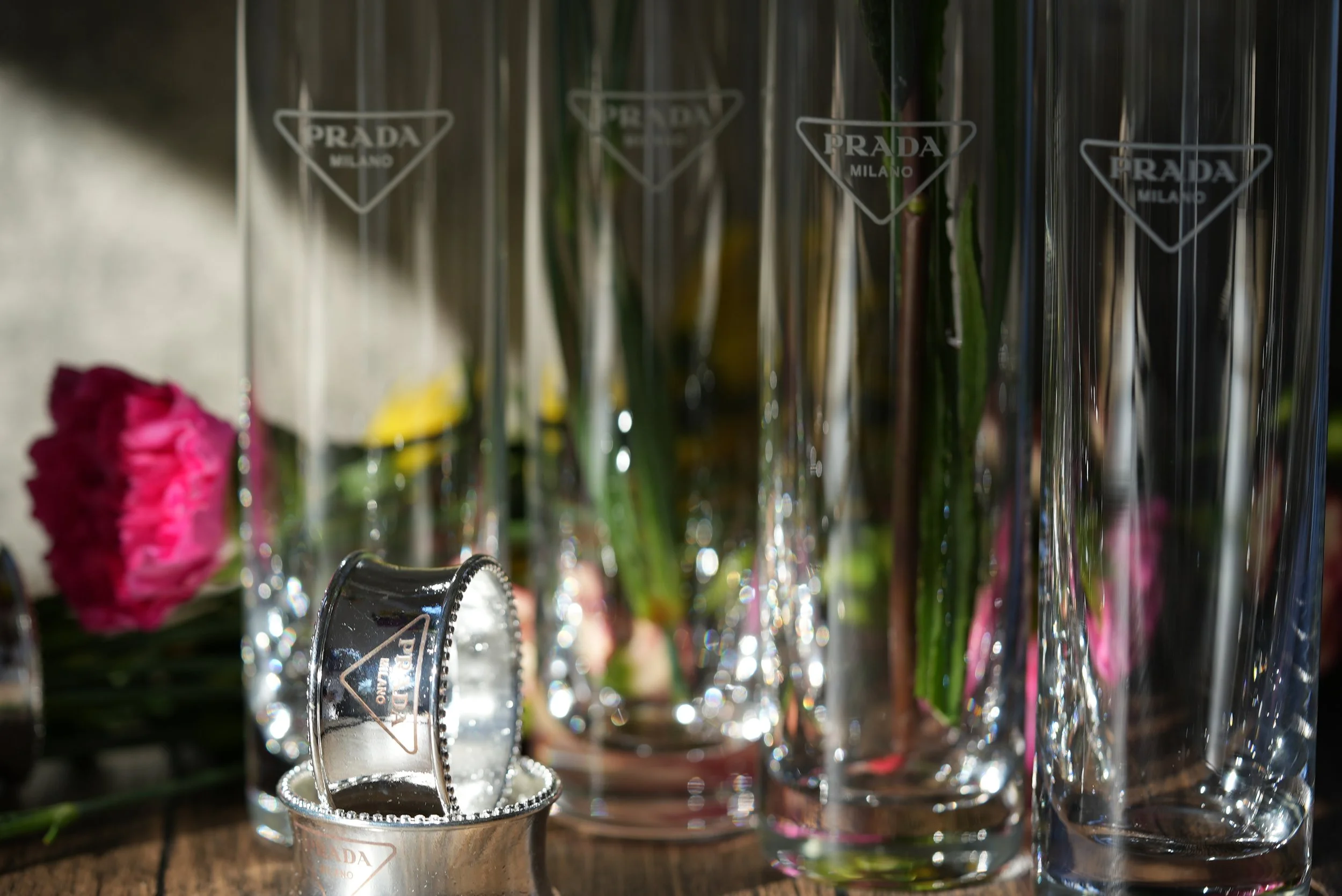 Close-up of elegant Prada Milano perfume bottles with flowers in the background
