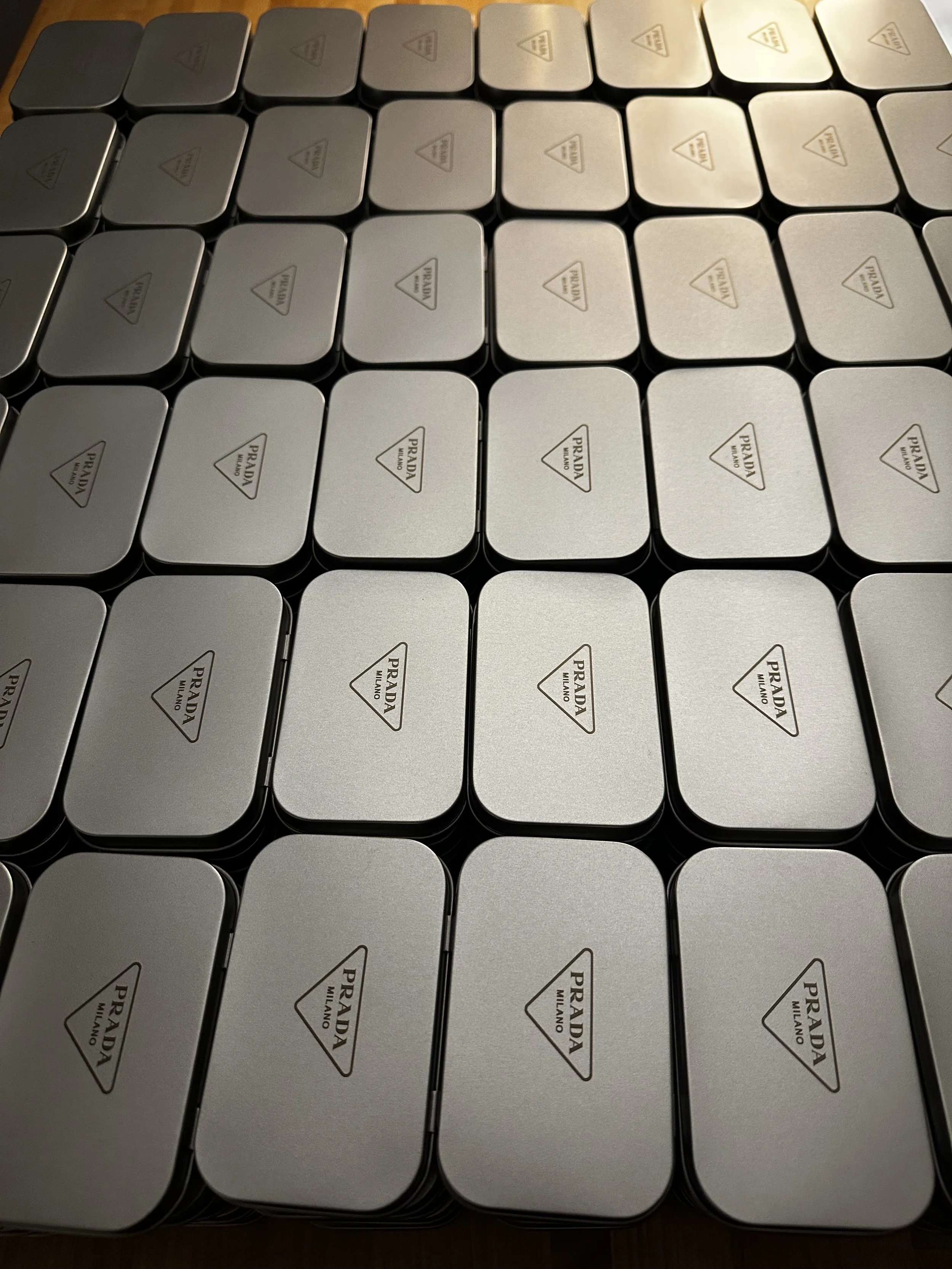A collection of Prada Milano tins arranged in a grid pattern.