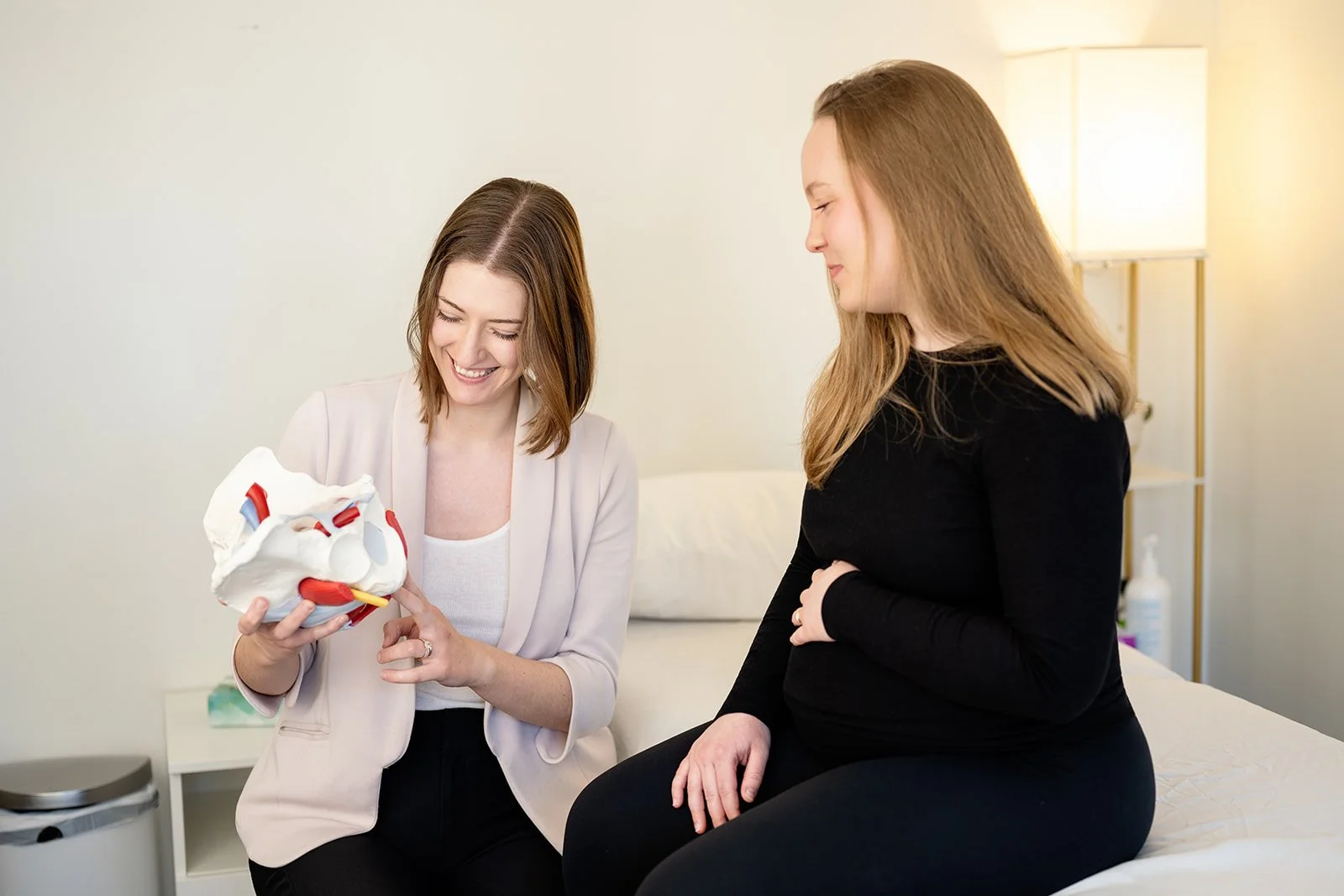 Pelvic health physical therapist using a pelvic model to educate a pregnant patient at Cultivate Your Wellbeing, serving Mequon and Brookfield, Wisconsin.