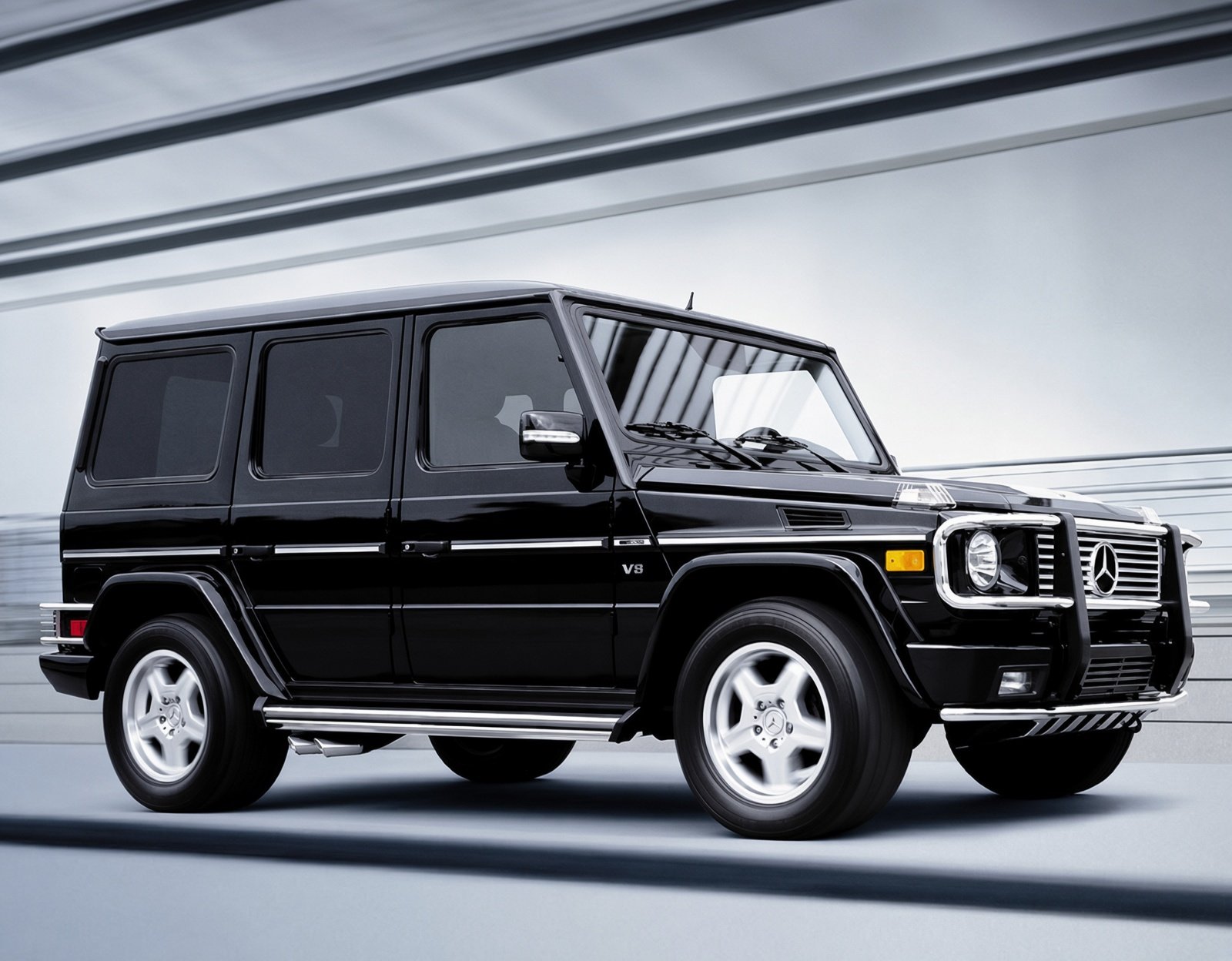 A black Mercedes-Benz G-Wagon SUV driving on a road with modern tunnel walls overhead.