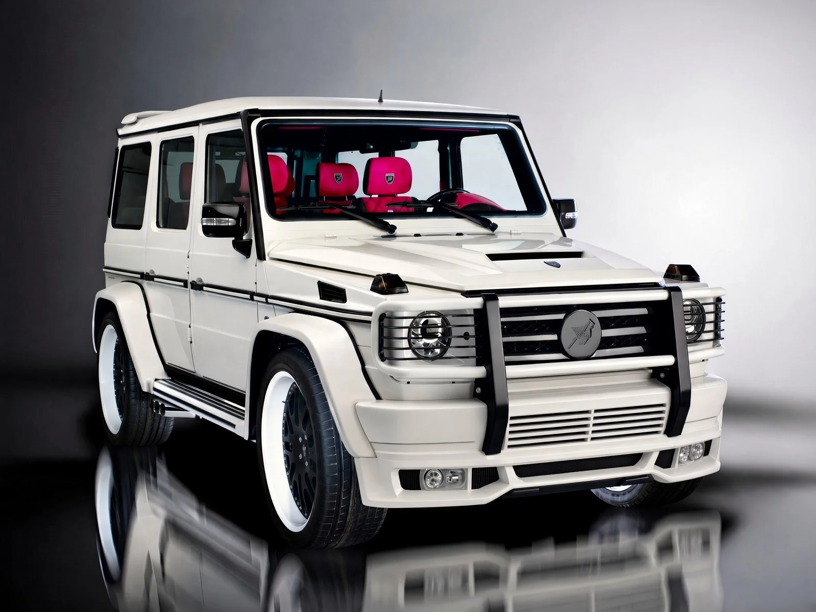 A white luxury SUV with a black grille guard, featuring red interior seats, and black accents, parked against a plain background.