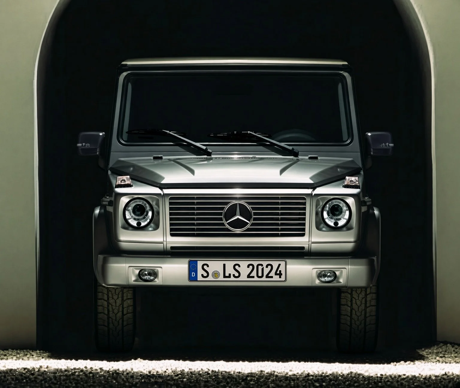 Front view of a silver Mercedes-Benz G-Class SUV parked in a dark garage.