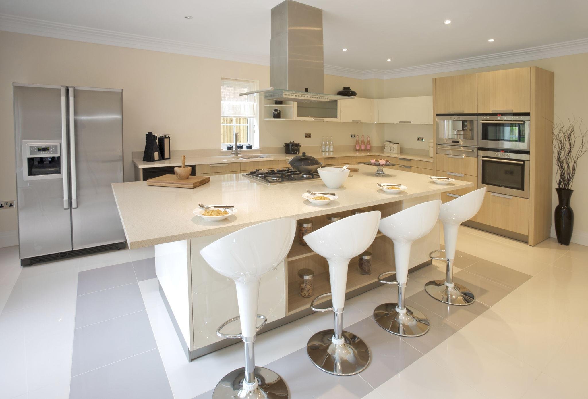 Bright modern kitchen with white island, bar stools, stainless steel appliances, wooden cabinets, and a window.