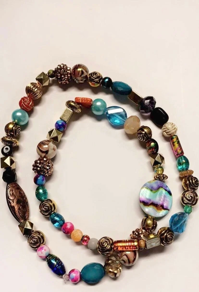Two colorful beaded necklaces with various shapes and sizes of beads, laid out on a white background.