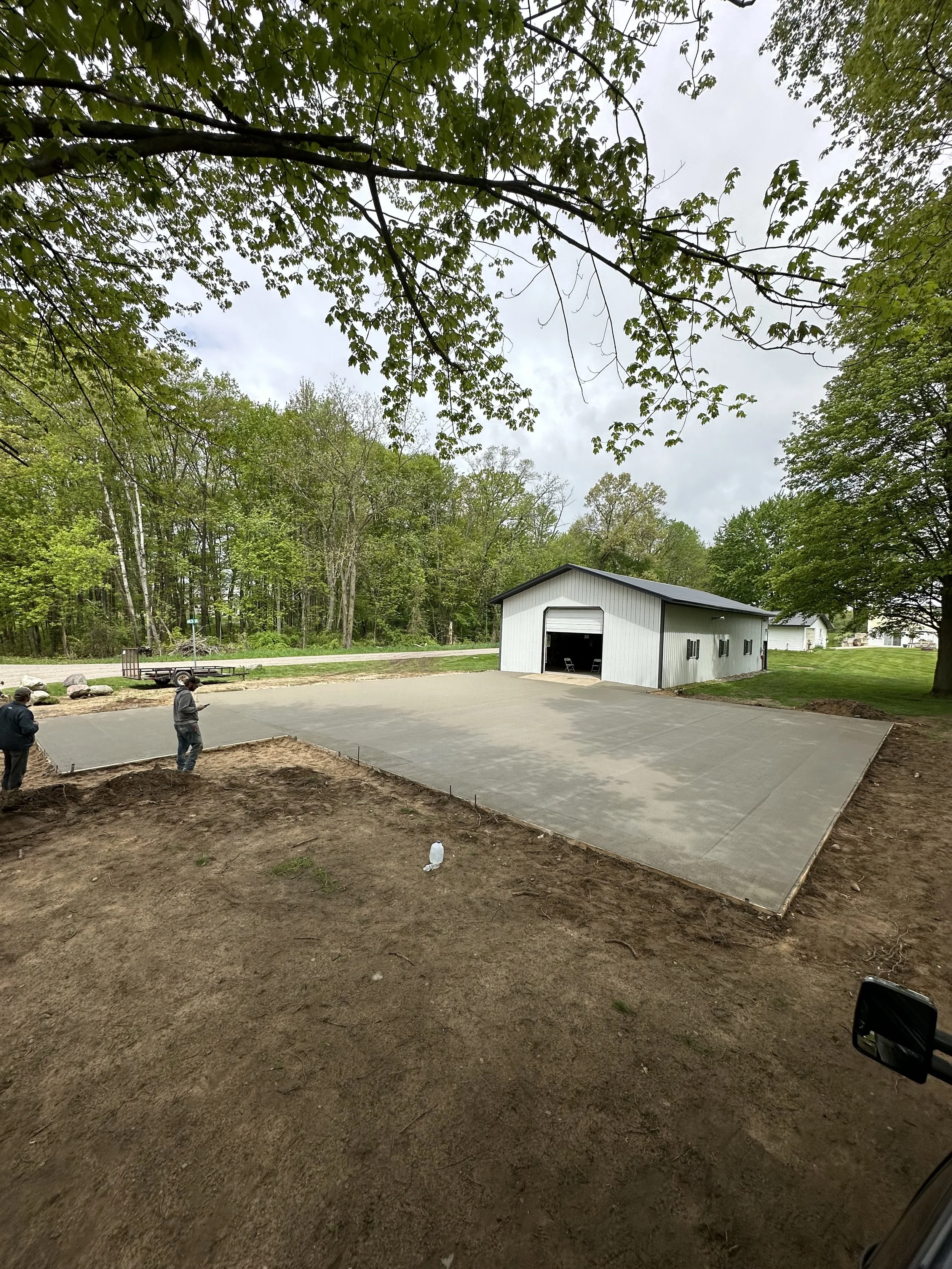 A newly poured concrete slab that approaches a pole barn.
