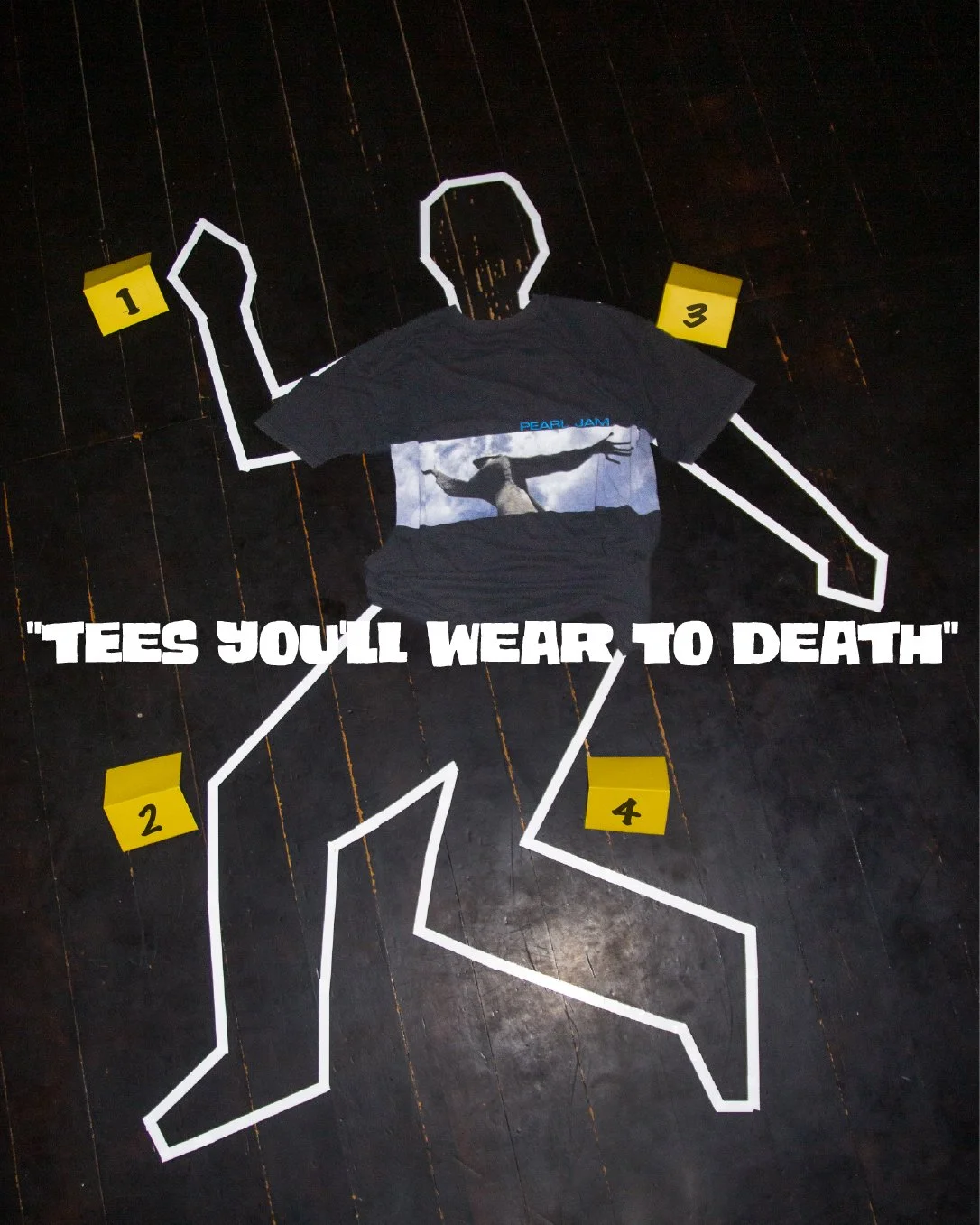 An outline of a person made with white tape on a dark floor, with a Pearl Jam T-shirt draped over the middle. There are four yellow numbered tags (1 to 4) pointing to different parts of the outline. The text 'TESS YOU'LL WEAR TO DEATH' is written in 