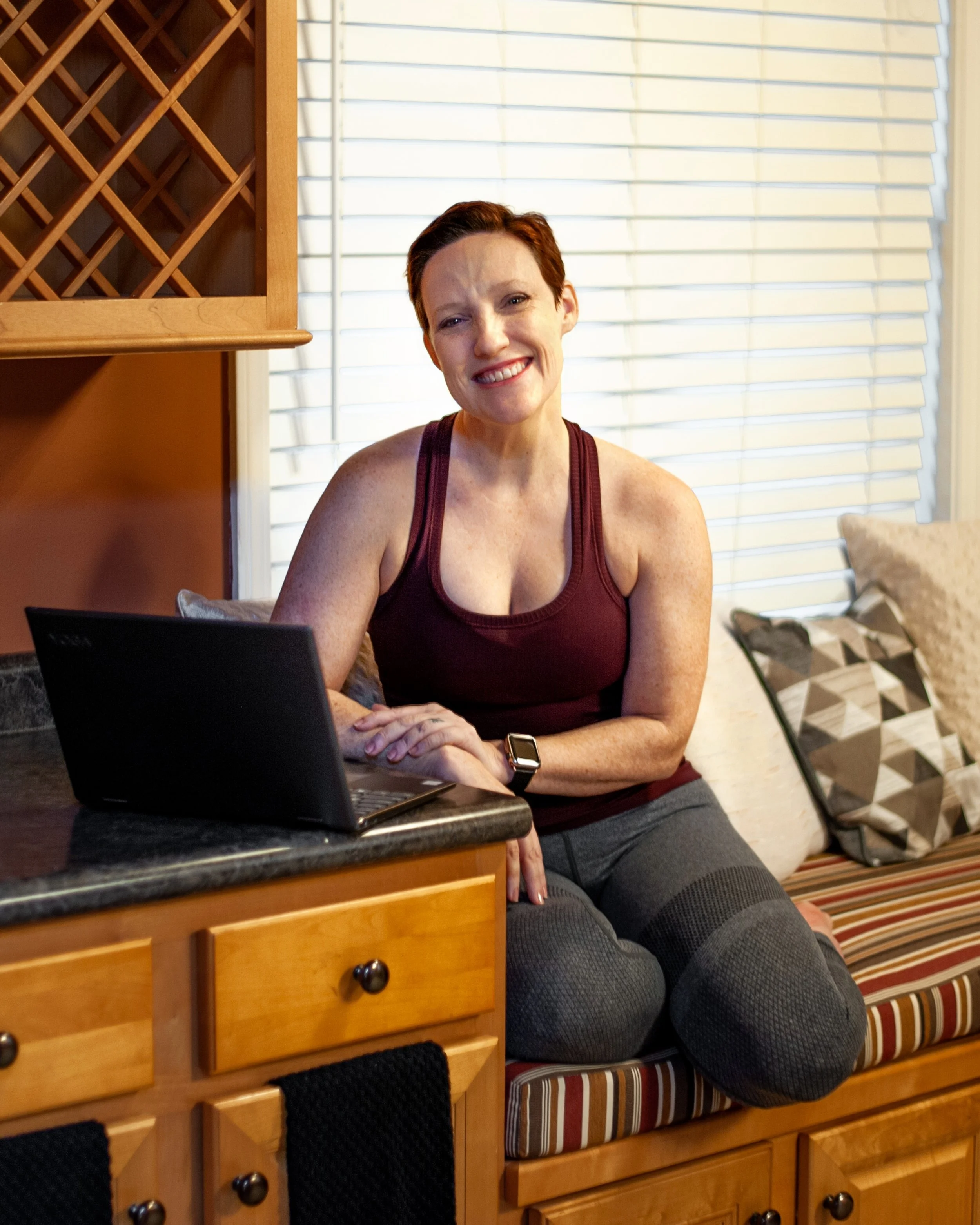 Kristyn McGeehan at her laptop smiling, representing online personal training