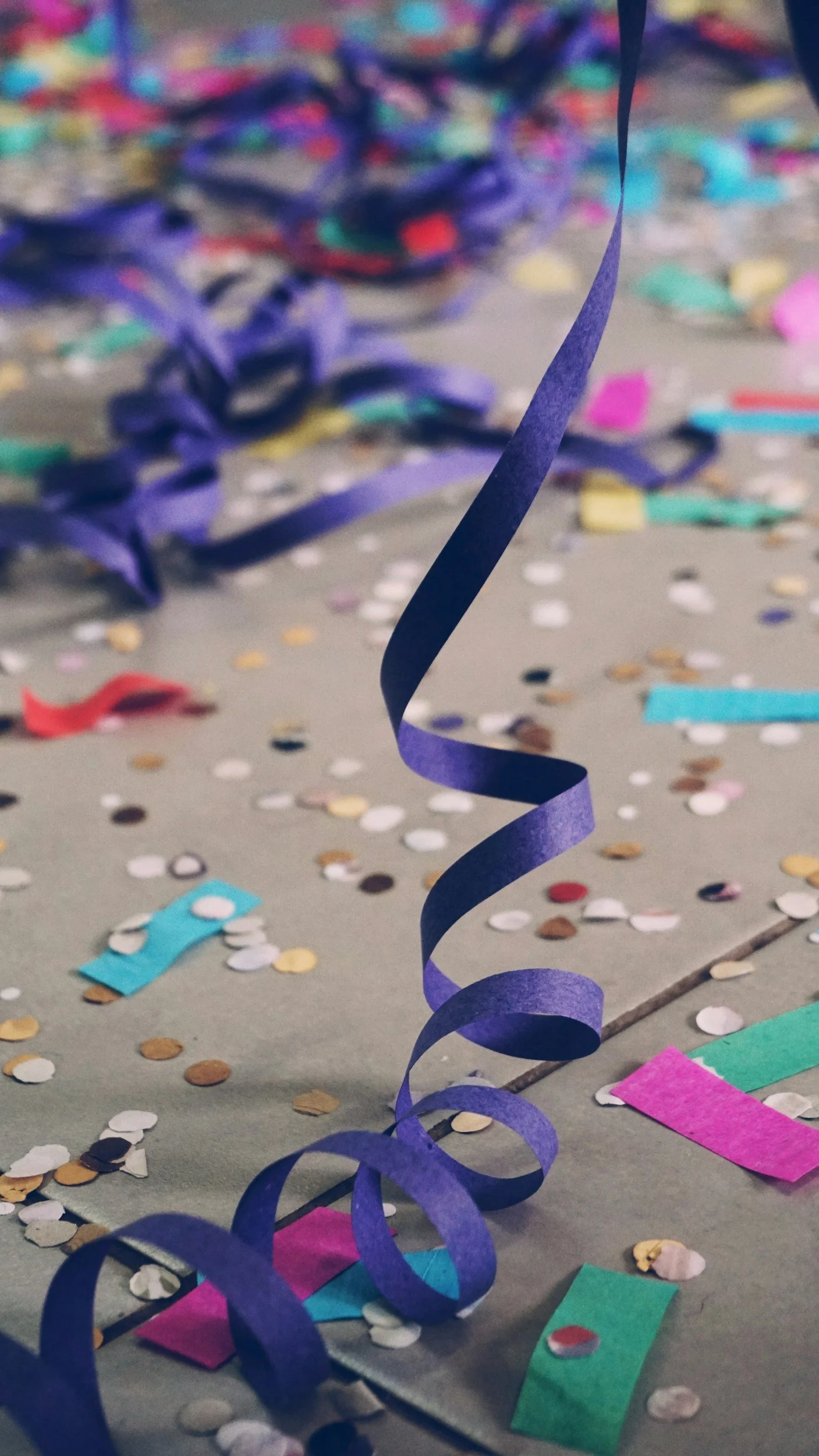 Colorful confetti, streamers, and paper decorations scattered on a surface at a celebration or party.