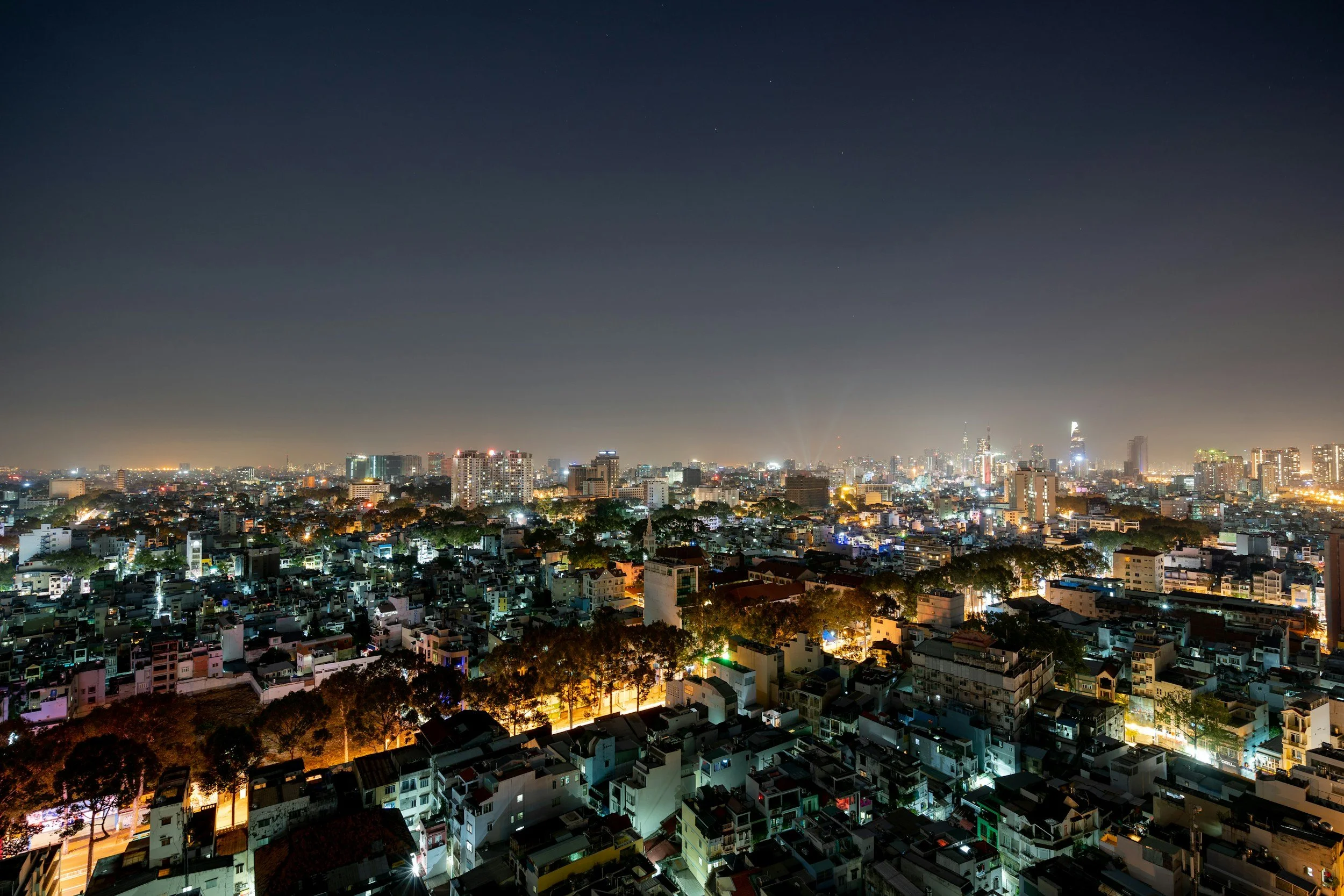 Nighttime cityscape with illuminated buildings and dark sky with stars.