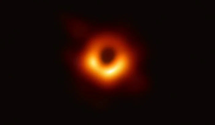 A glowing orange ring around a dark central shadow, the first-ever image of a black hole, in galaxy M87.