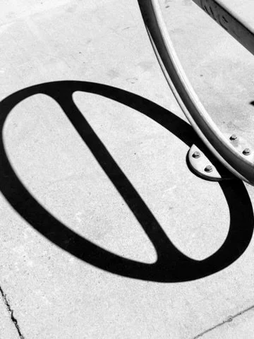 Close-up of a bicycle wheel casting a circular shadow on the ground.
