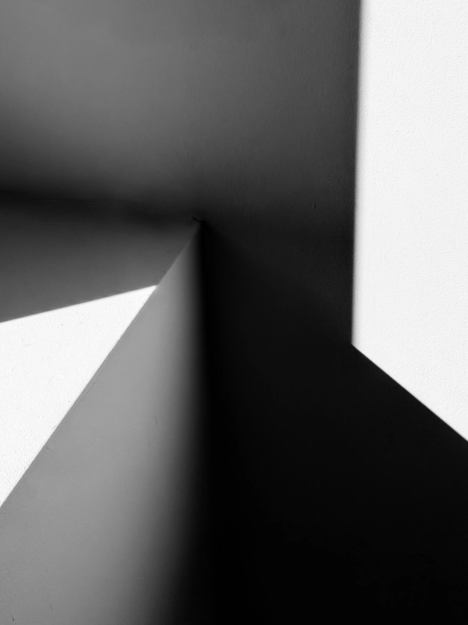 Black and white abstract shadows with geometric shapes on a wall.