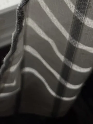 Close-up of a plaid fabric curtain with horizontal and vertical stripes in shades of gray, black, and white.
