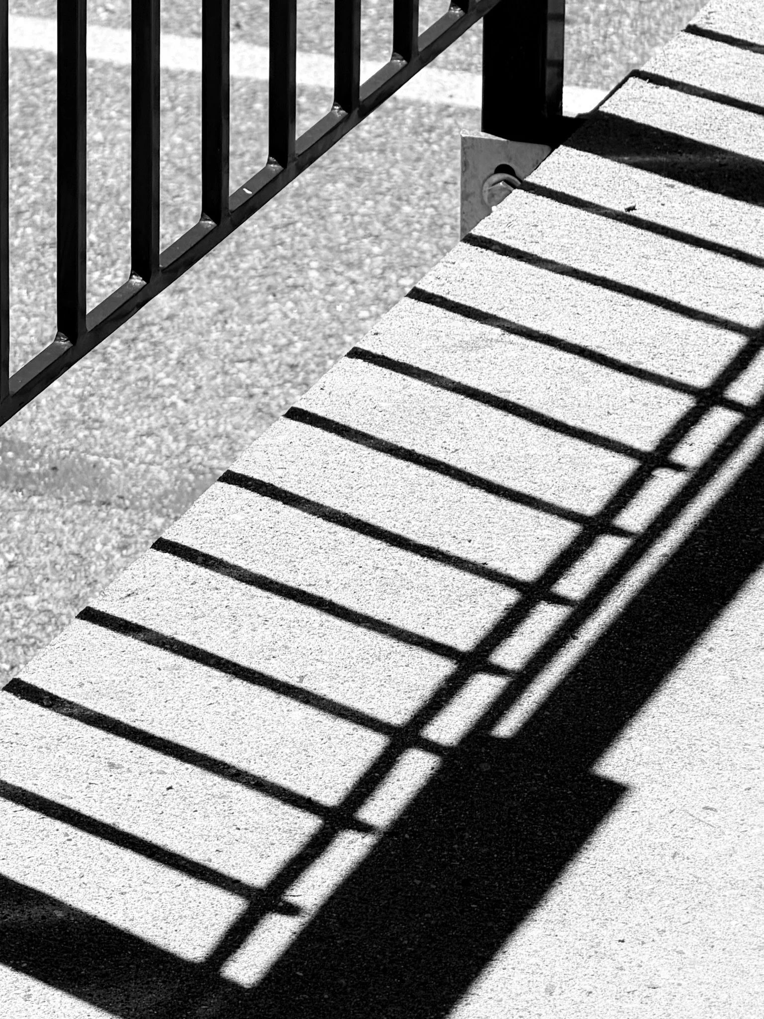 Black metal railing casting long shadows on a concrete surface.