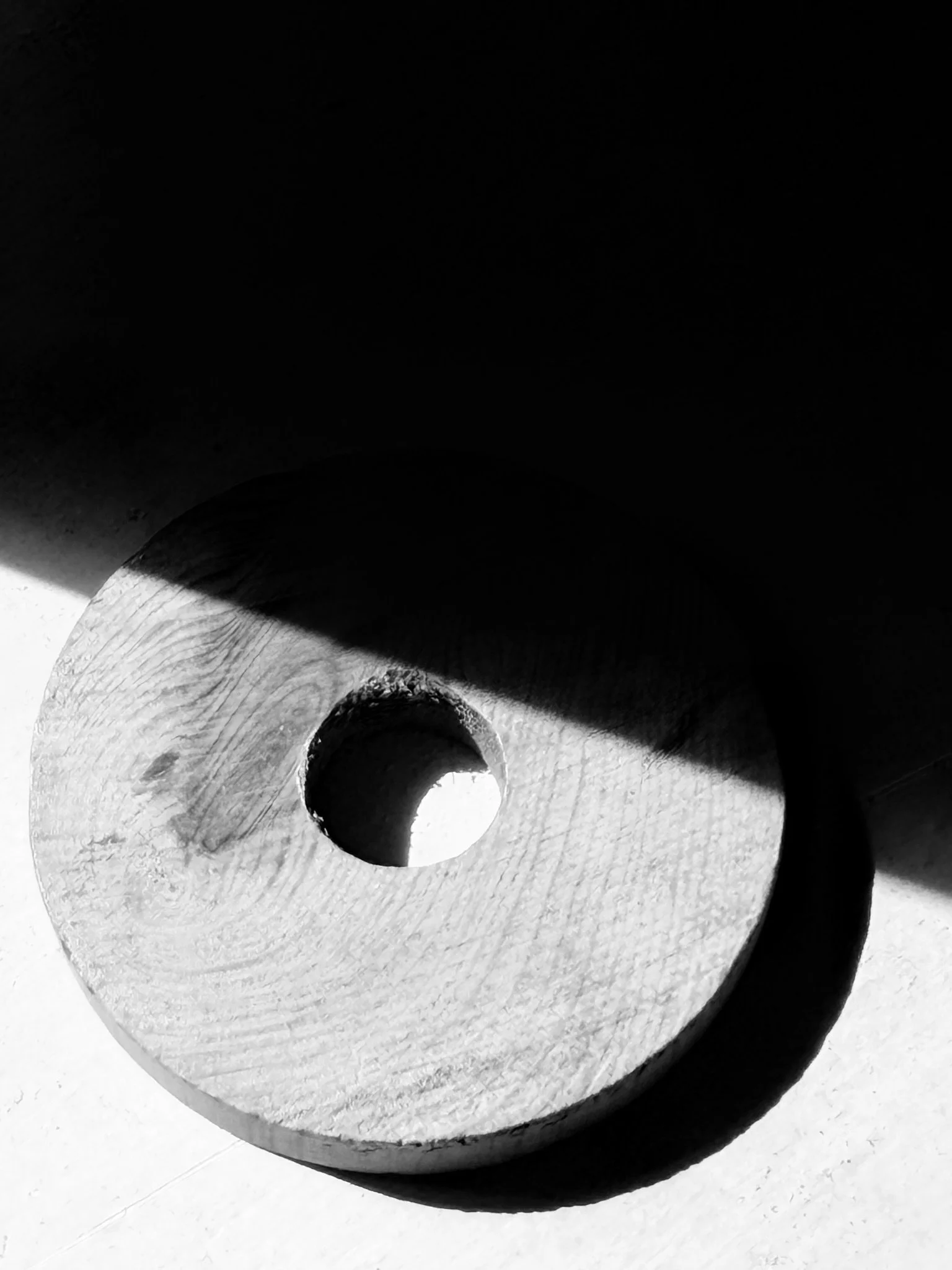 Close-up black and white photograph of a cylindrical metallic pipe with a hollow center, showcasing the textured surface and inner walls.