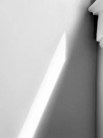 Close-up of a window with sunlight casting a shadow on the wall.