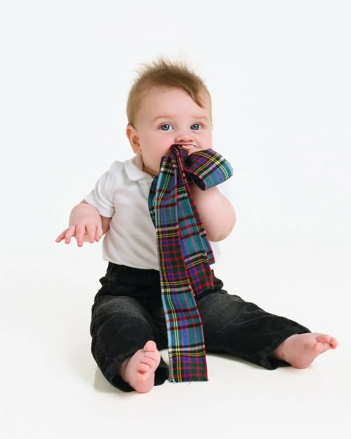 Baby chewing a tartan sash